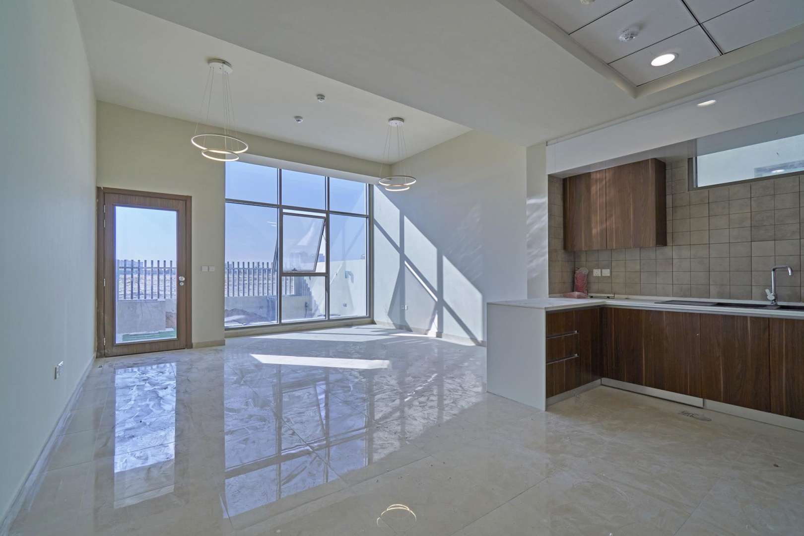 Empty room with wooden flooring and large window in Al Furjan townhouse, Murano Residences
