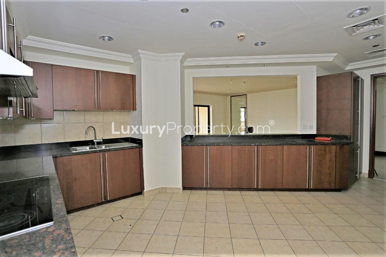 Alt text: "Golden Mile apartment buildings and monorail in Palm Jumeirah, Dubai, sunny day view.",Spacious kitchen in 3-bedroom apartment, Golden Mile, Palm Jumeirah, with modern cabinetry and countertops