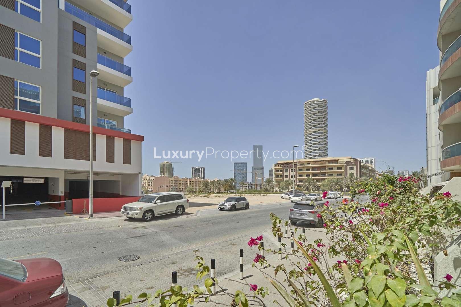 Studio apartment interior with bed, sofa, and balcony view in Knightsbridge Court, JVC