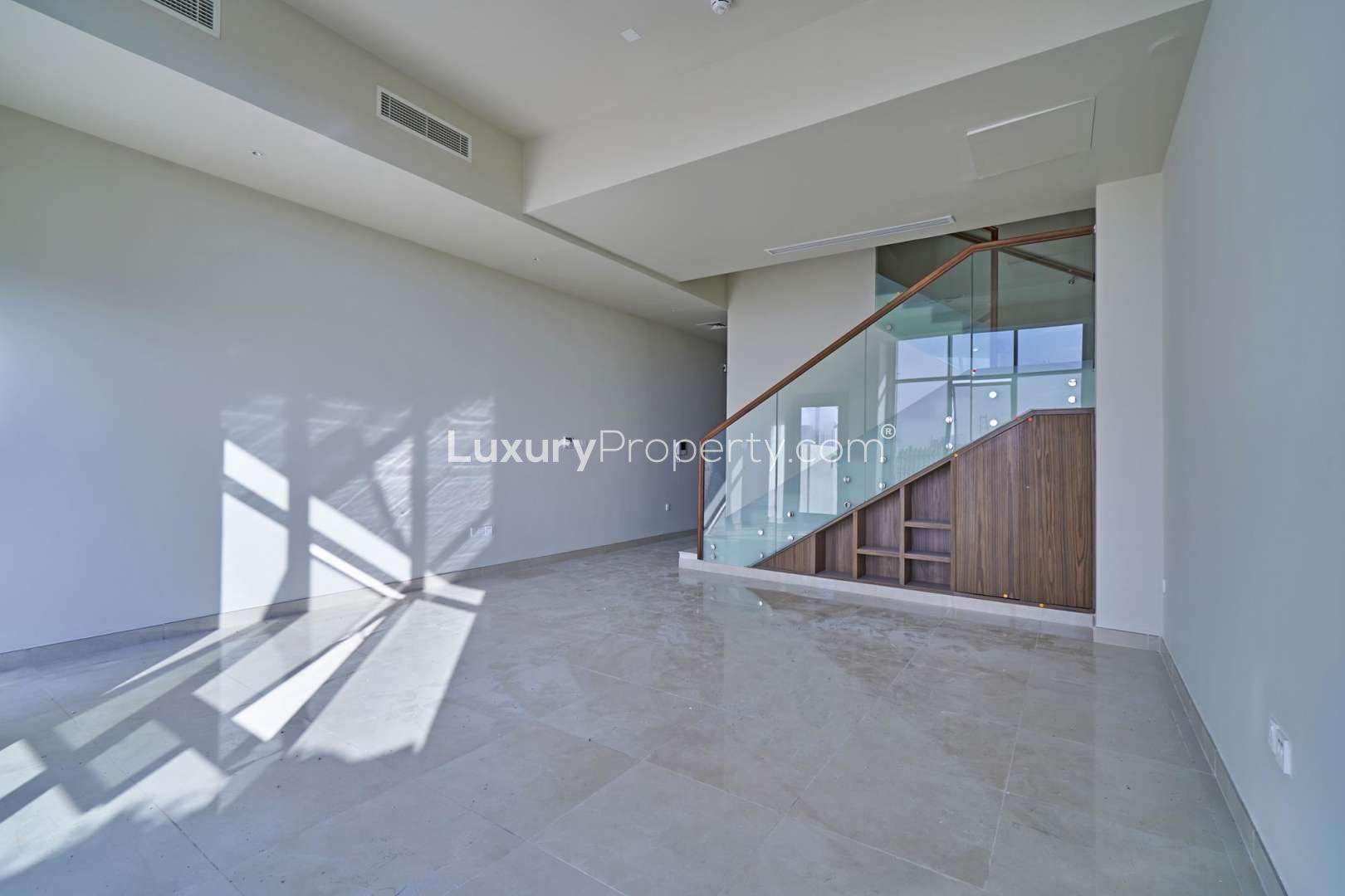 Modern living area with glass staircase in Al Furjan townhouse, Murano Residences