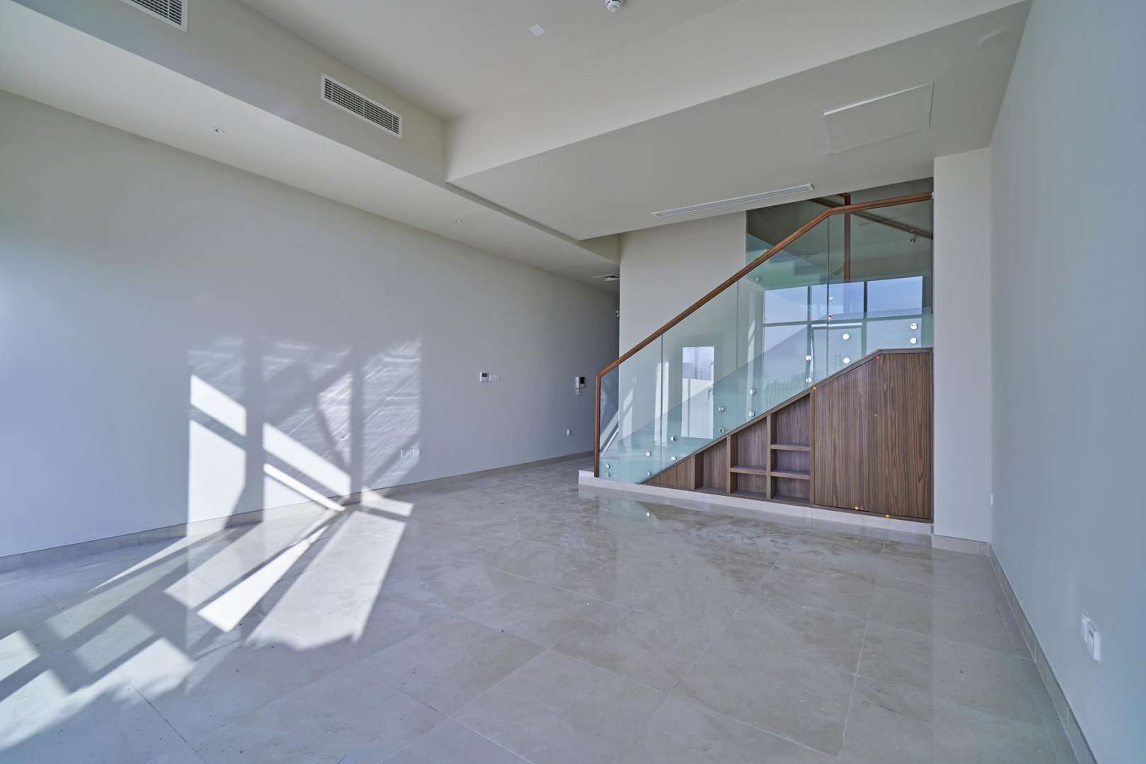 Modern living area with glass staircase in Al Furjan townhouse, Murano Residences