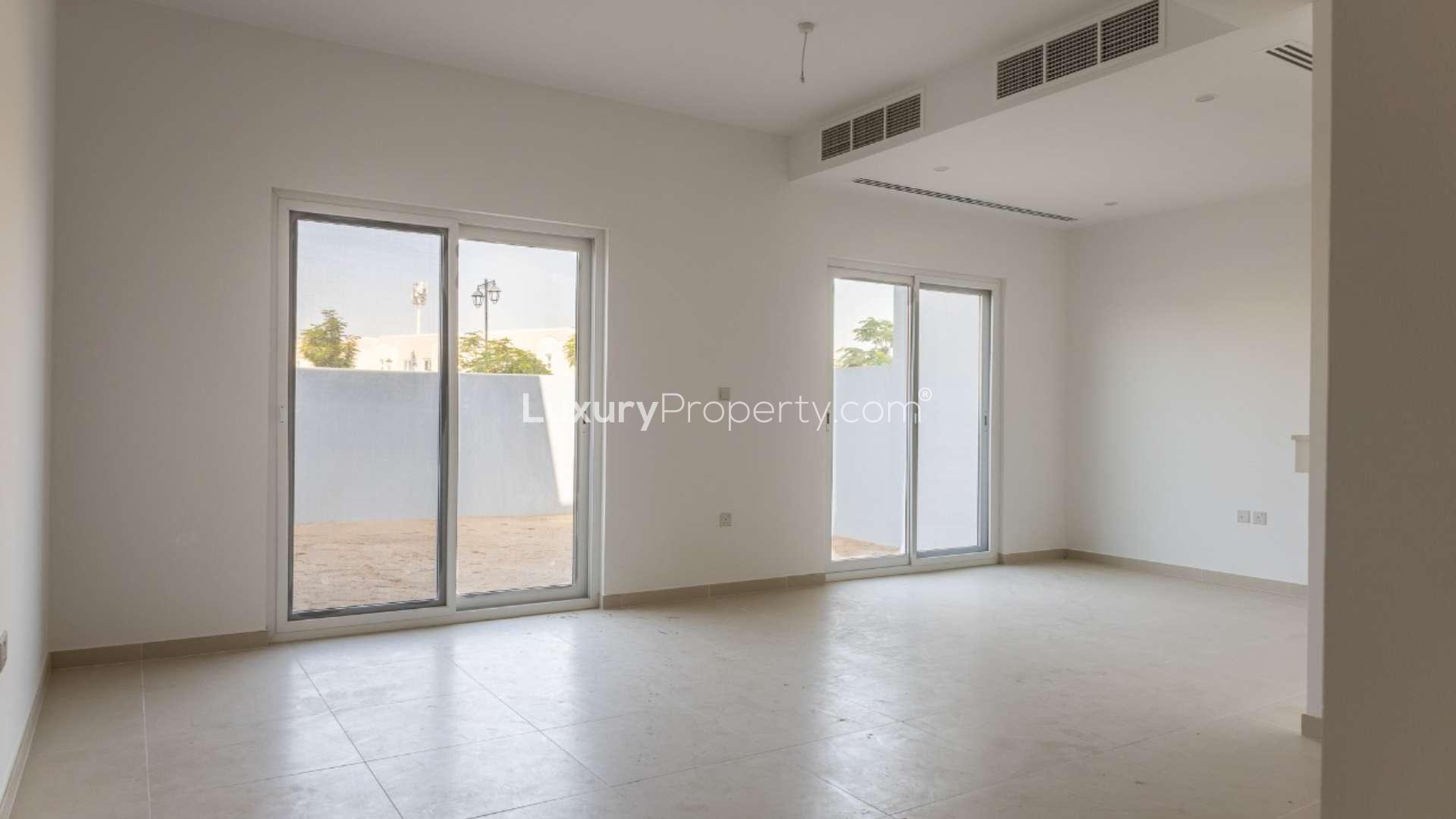 Modern townhouse interior with staircase, open kitchen, and tiled floor in Villanova, Dubai Land