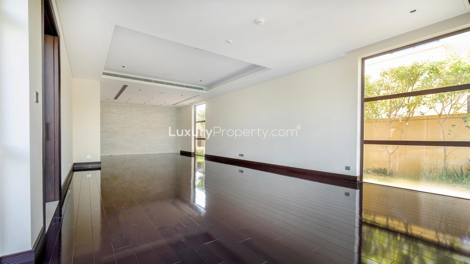 "Spacious living room in 5-bedroom villa, Earth, Jumeirah Golf Estates, with pool view.",Spacious living room with large window in Jumeirah Golf Estates villa for rent