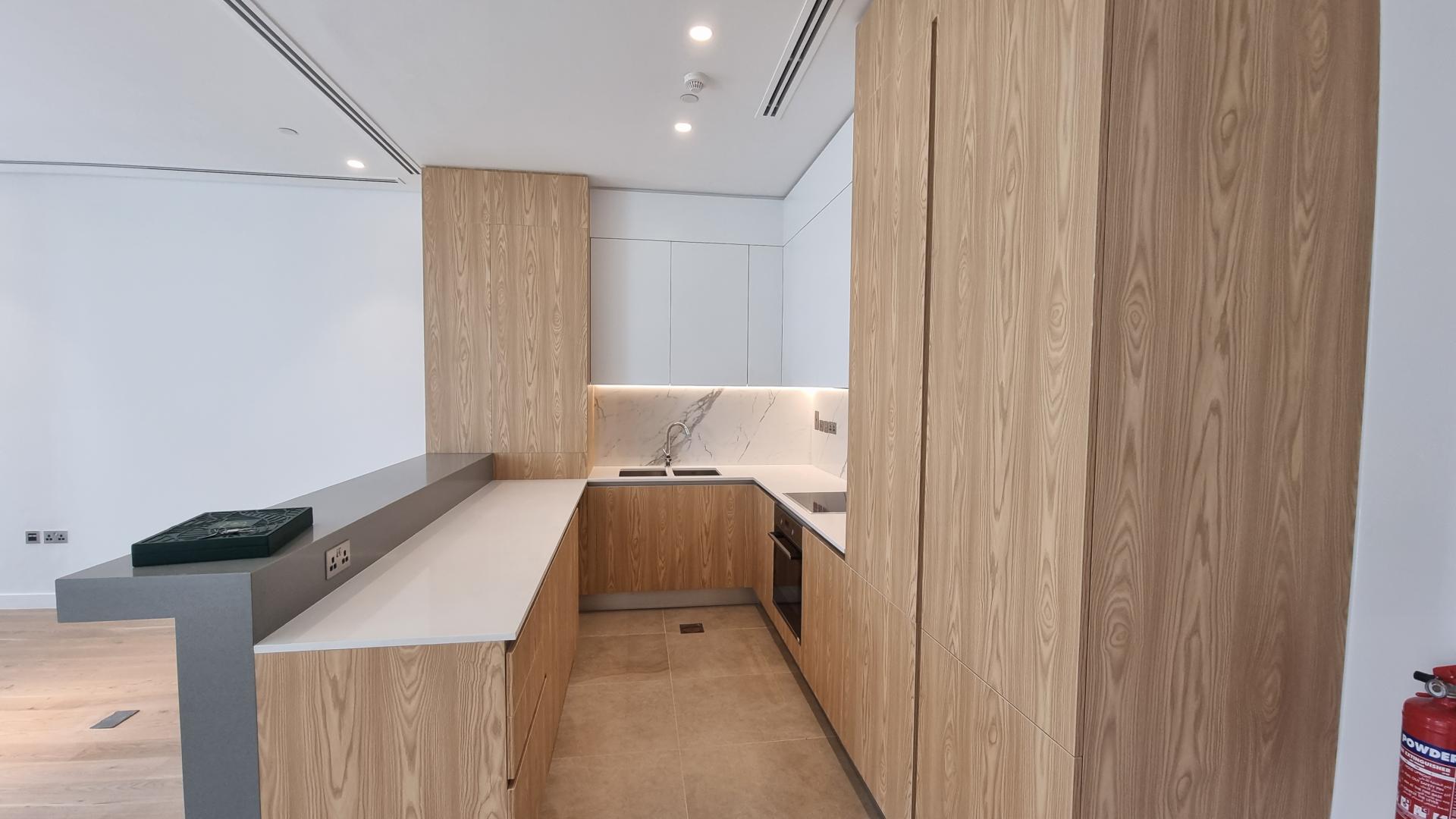 Modern kitchen with wood cabinets in Al Barari 1-bedroom apartment for sale