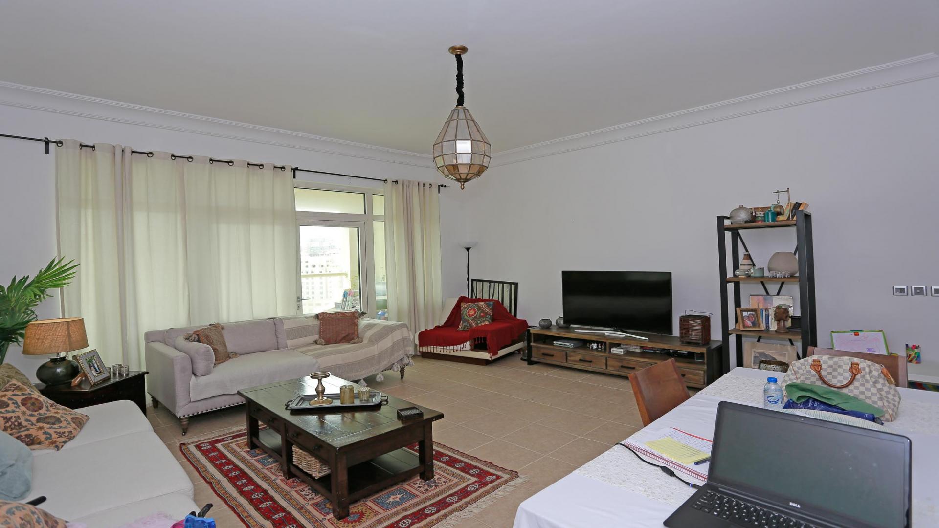 "High-floor balcony view from Shoreline Apartments, Palm Jumeirah, showcasing urban skyline and seating.",Spacious living room in two-bed apartment, Shoreline Apartments, Palm Jumeirah, high floor unit