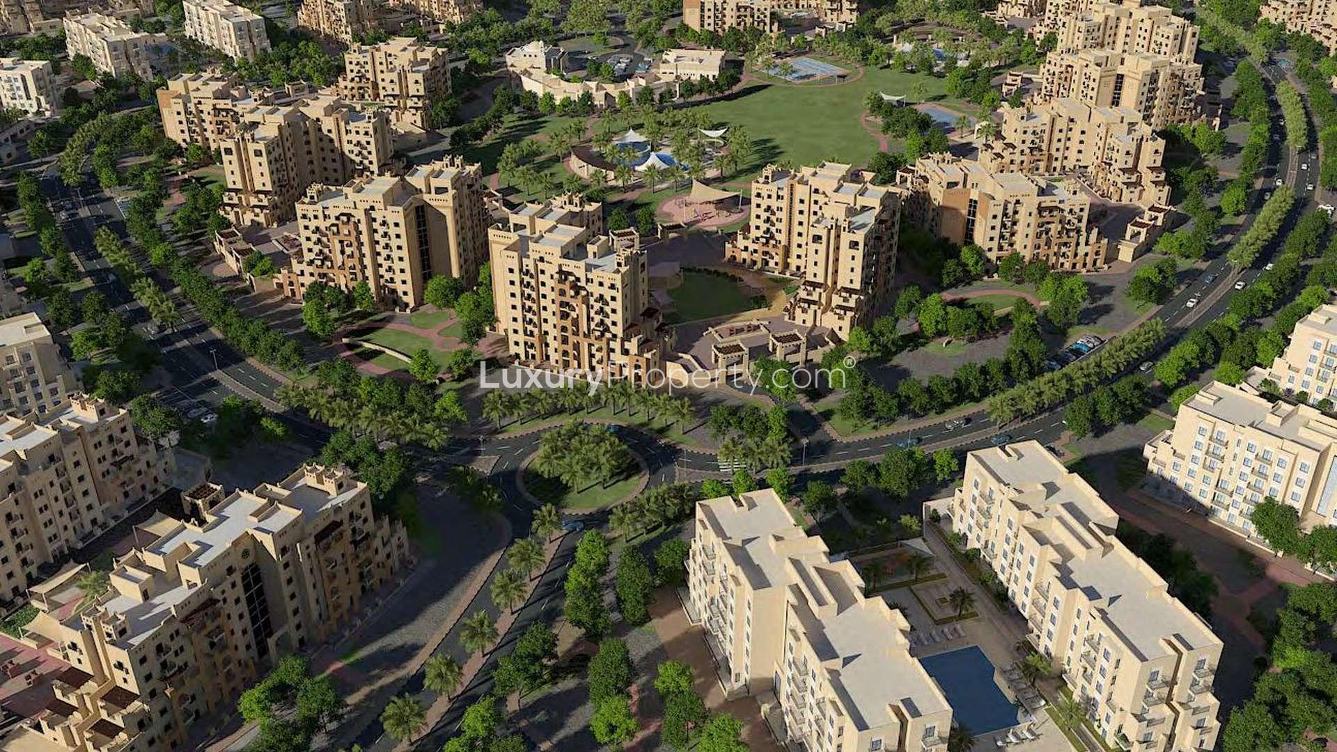 Modern apartment building in Remraam, Dubailand, featuring multiple balconies and lush landscaping