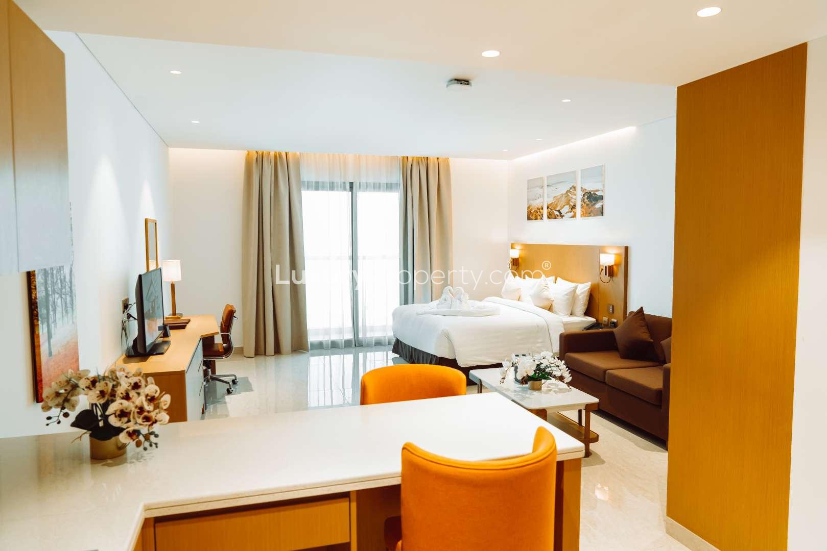 Studio apartment interior with twin beds in deluxe hotel, natural light from large window