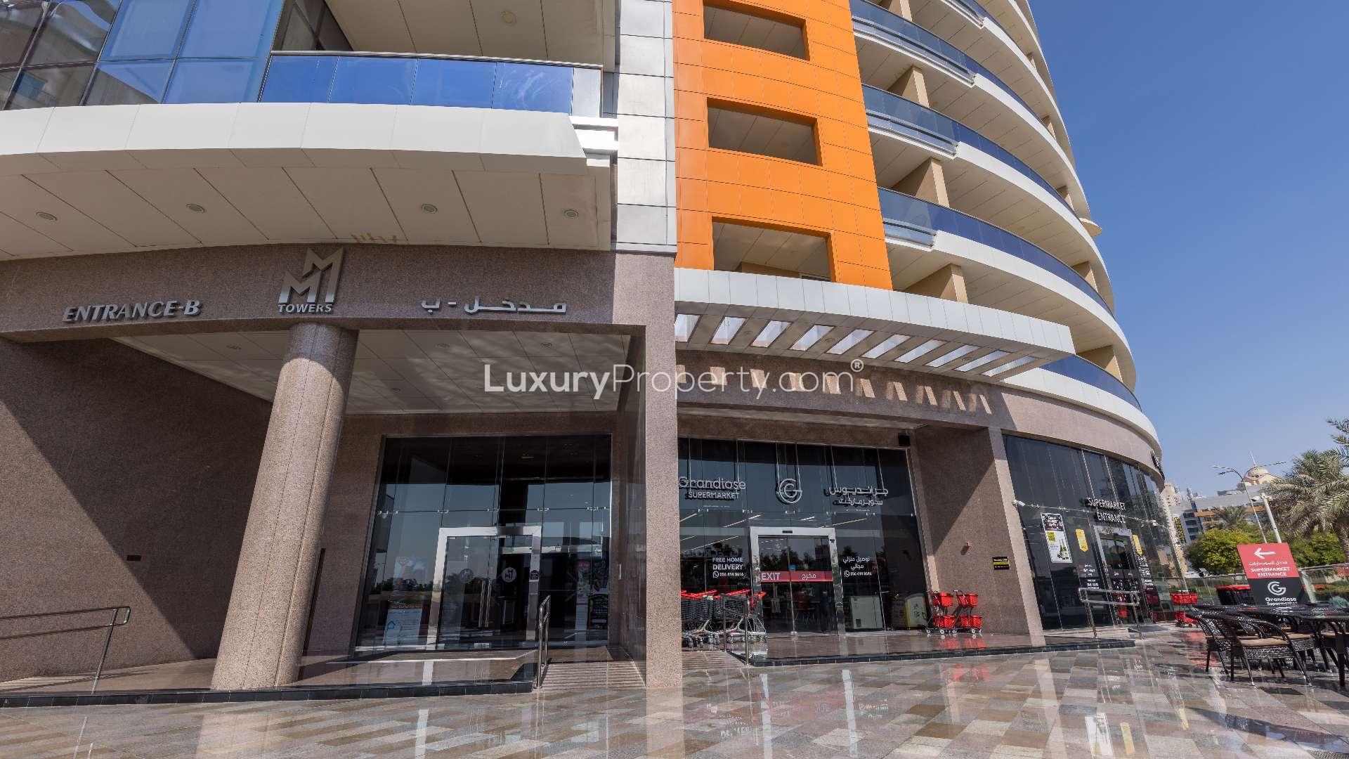 Twin-tower apartment building in Dubai Silicon Oasis, MM Towers, lush greenery, blue sky