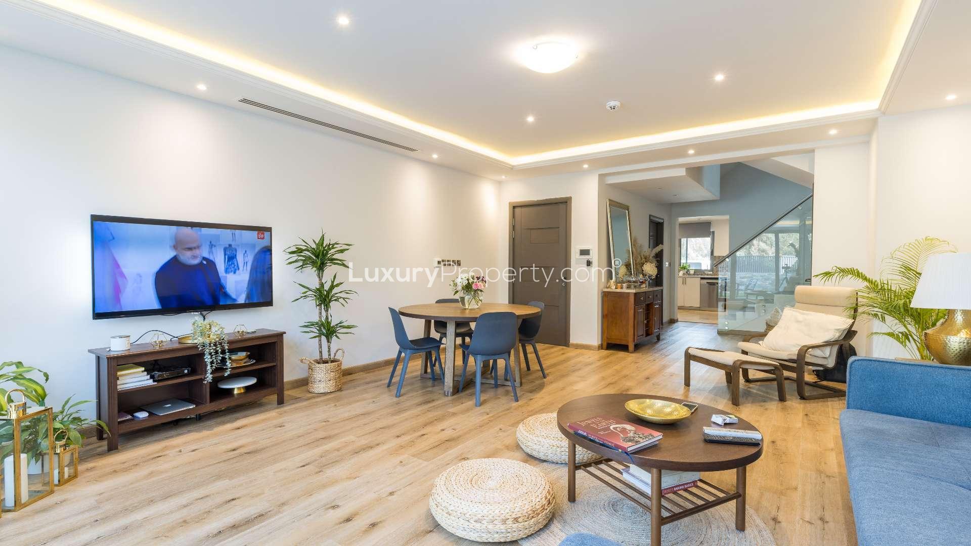 Luxurious living room in Jumeirah Village Circle townhouse, featuring garden views through large windows