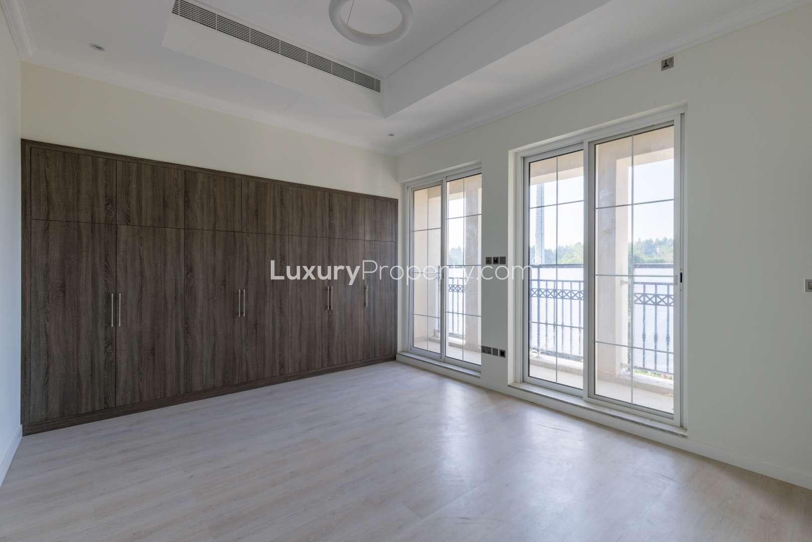 "Elegant four-bedroom villa exterior in Jumeirah Golf Estates, Fire community, for sale.",Empty bedroom with large windows and built-in wardrobe in Jumeirah Golf Estates villa