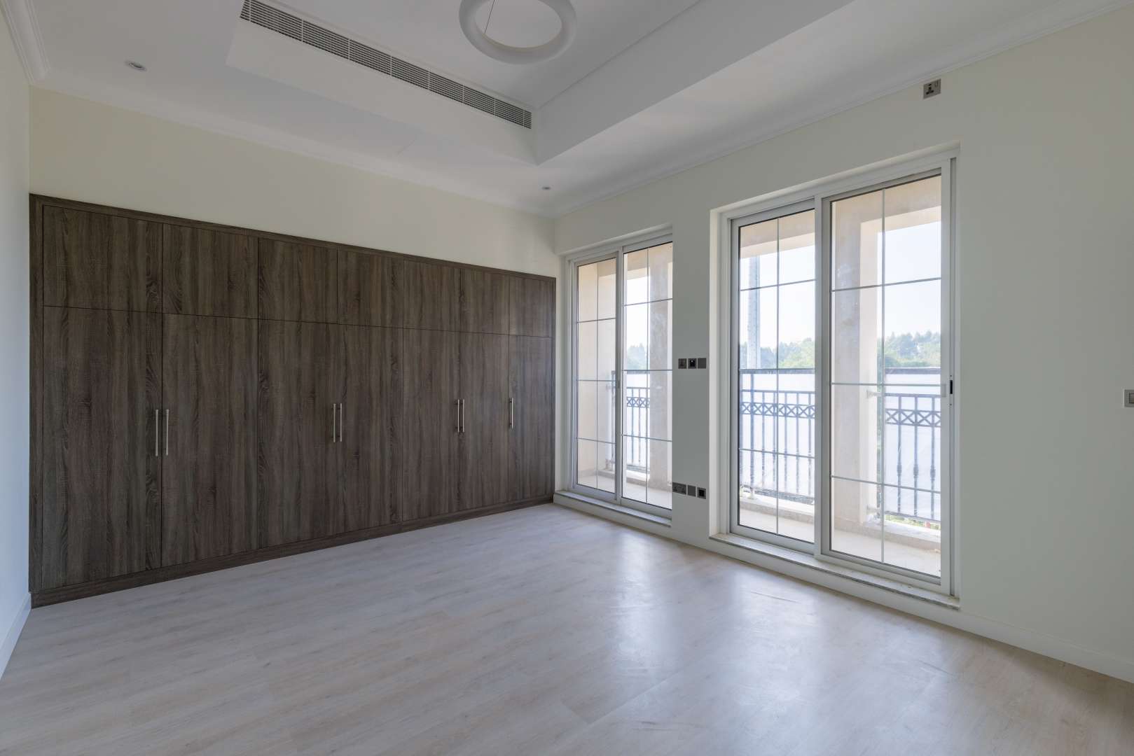 "Elegant four-bedroom villa exterior in Jumeirah Golf Estates, Fire community, for sale.",Empty bedroom with large windows and built-in wardrobe in Jumeirah Golf Estates villa