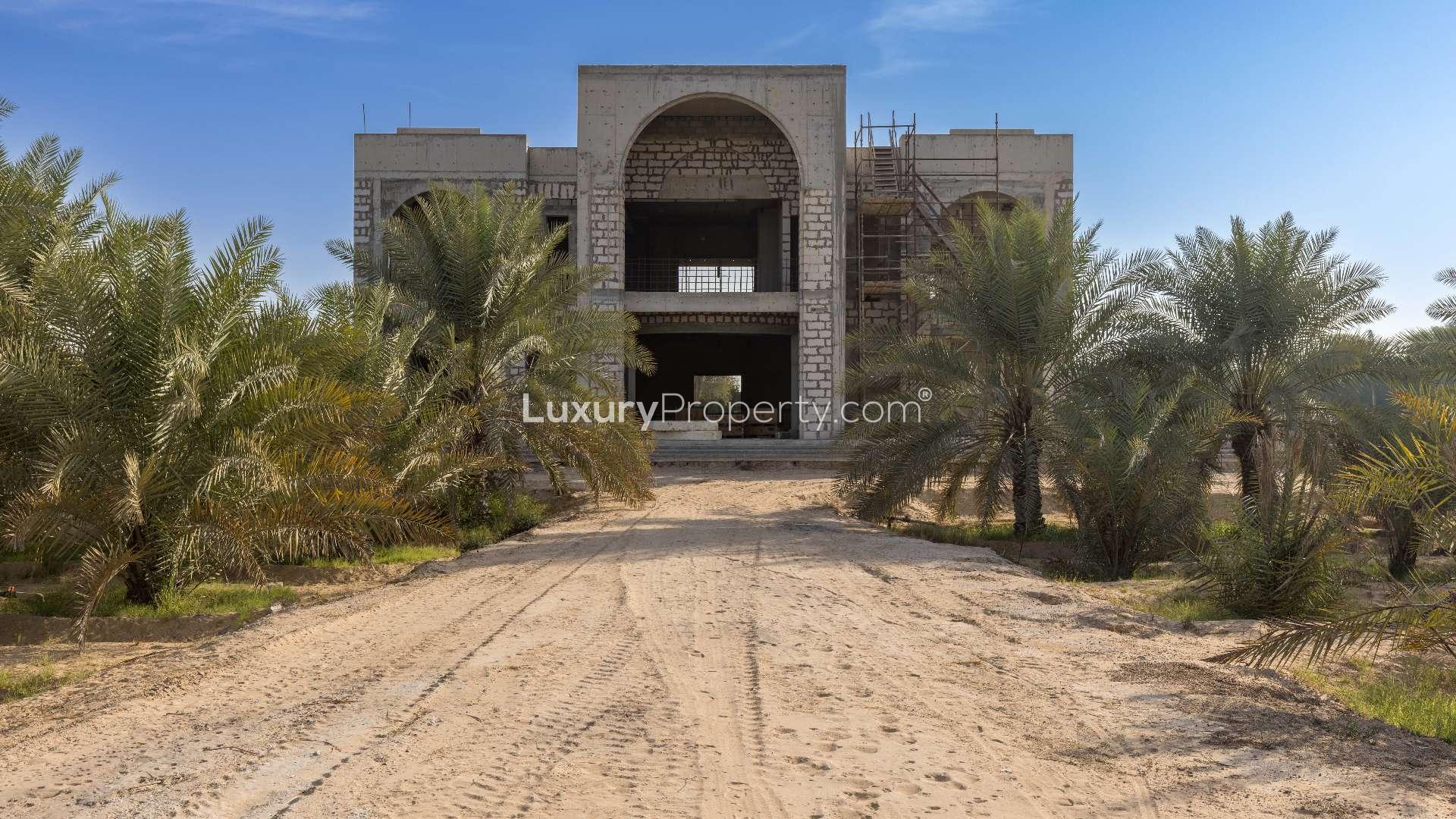 Exterior view of Al Awir Village villa for sale, surrounded by trees and desert landscape