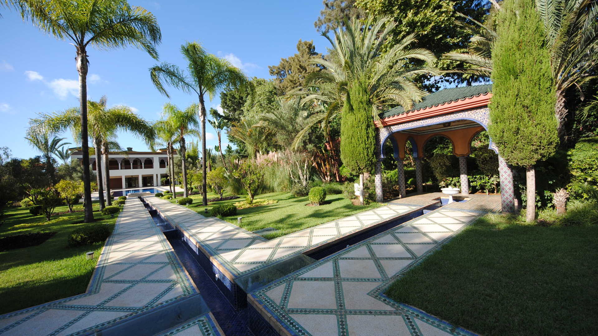 Luxurious Moroccan estate garden with palm trees and pathway in Rabat villa for sale