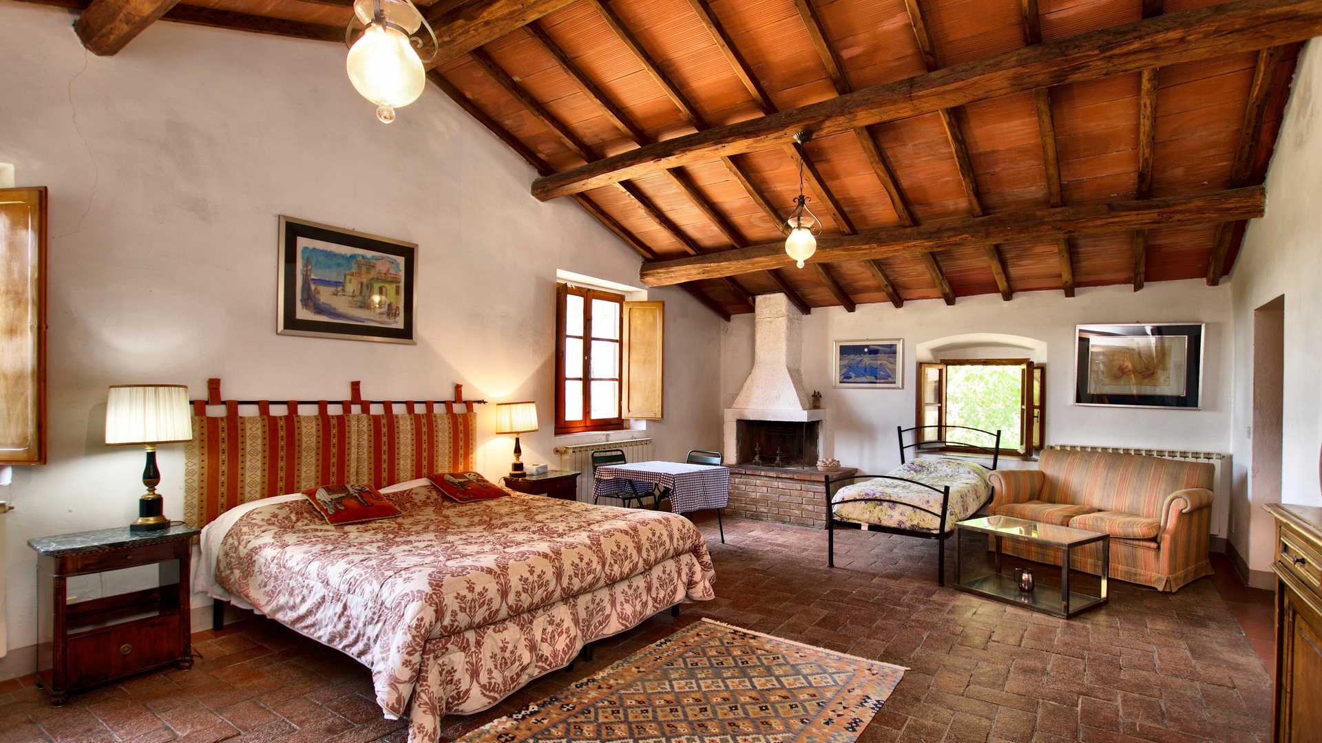 16th Century Chianti Villa Bedroom with Rustic Beams and Elegant Chandelier in Tuscany