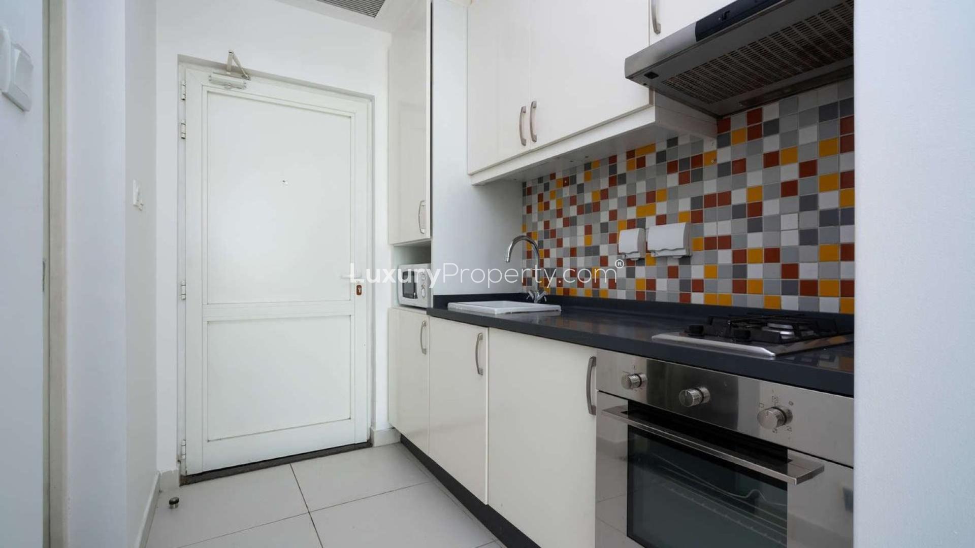 N/A,Modern kitchen in Palm Jumeirah studio apartment, featuring colorful tiled backsplash and sleek appliances