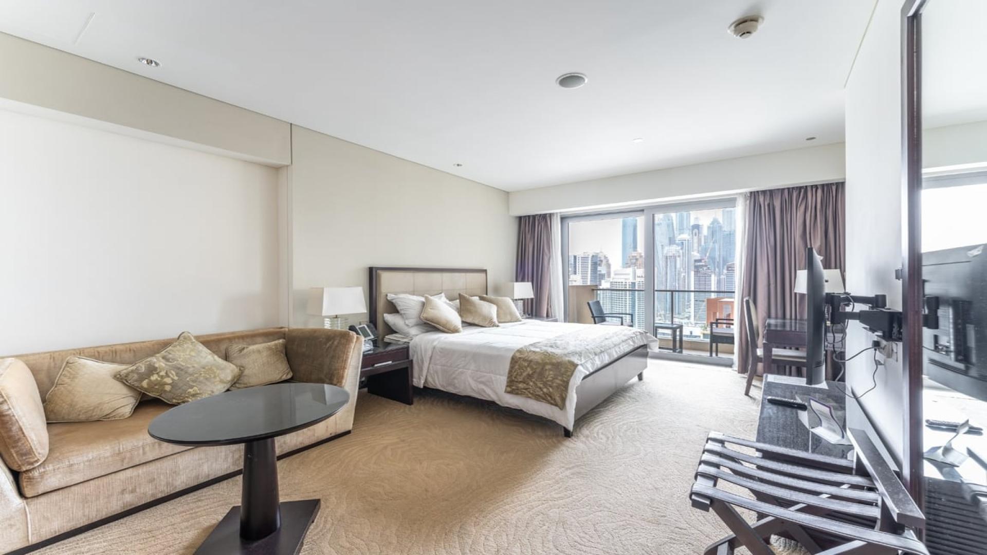 Furnished studio apartment interior in The Address Dubai Marina, featuring a cozy bed and decor