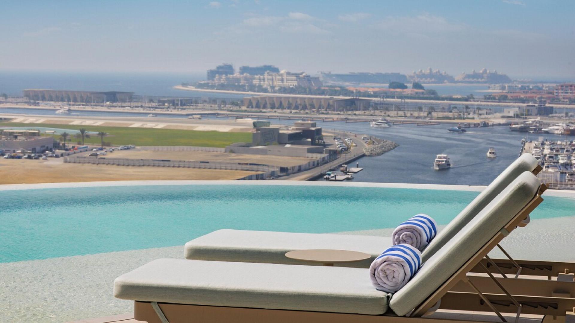 Luxurious Dubai Marina apartment terrace with ocean view, lounge chairs, and sunset ambiance