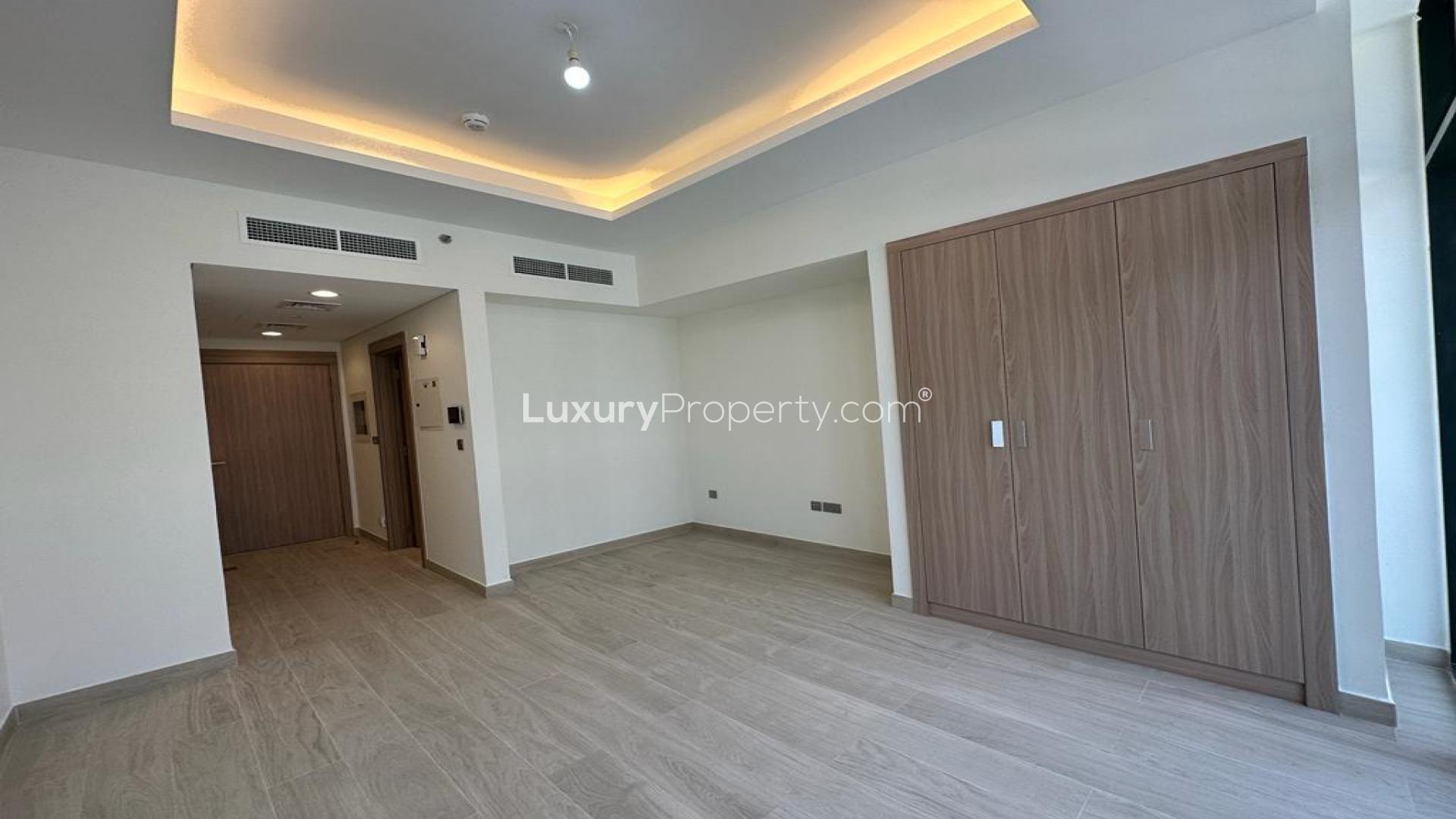 Spacious studio apartment interior with large windows in Azizi Victoria, MBR City for sale