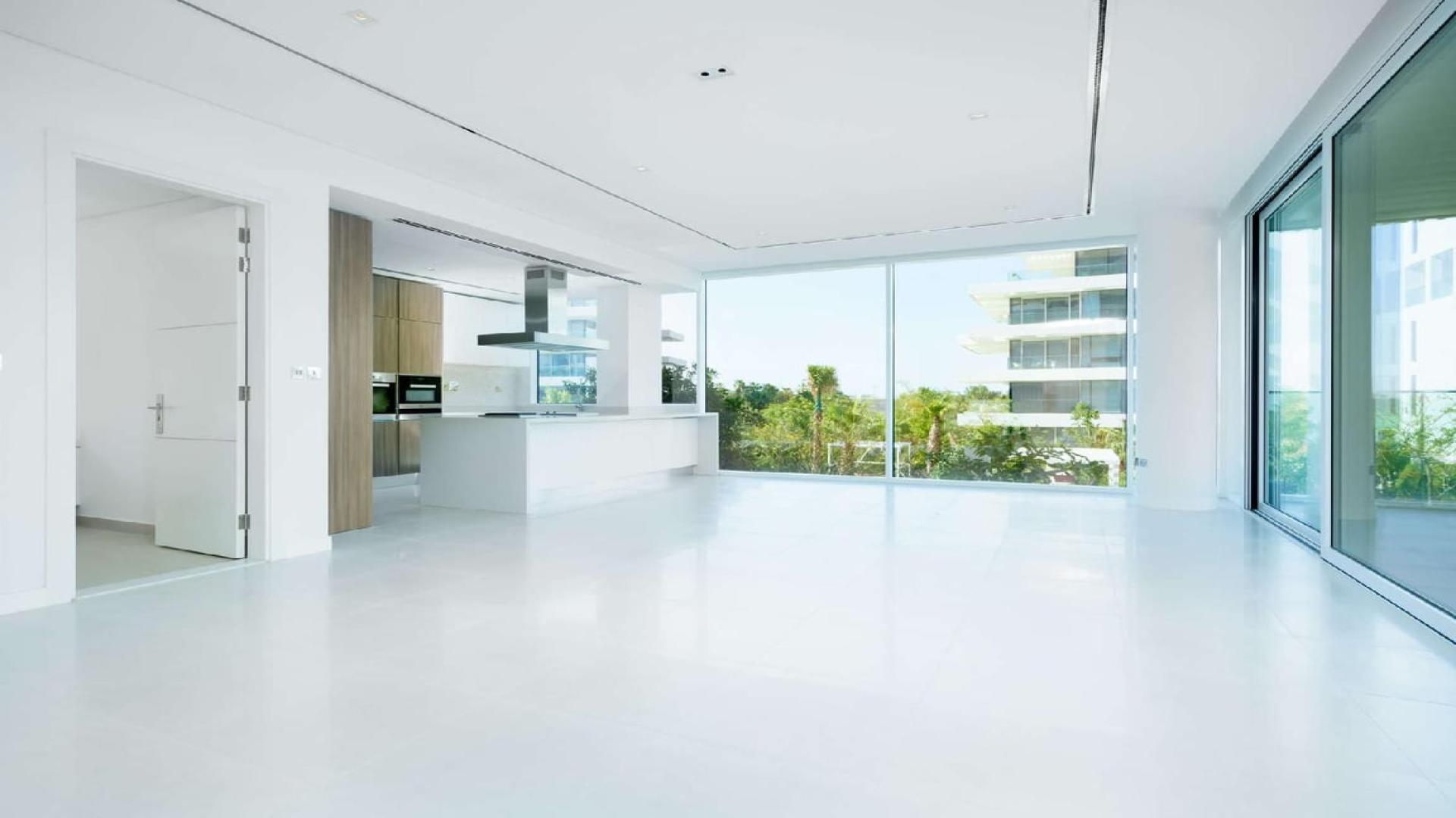 Modern open-plan kitchen and living area with large windows in Ashjar apartment, Al Barari