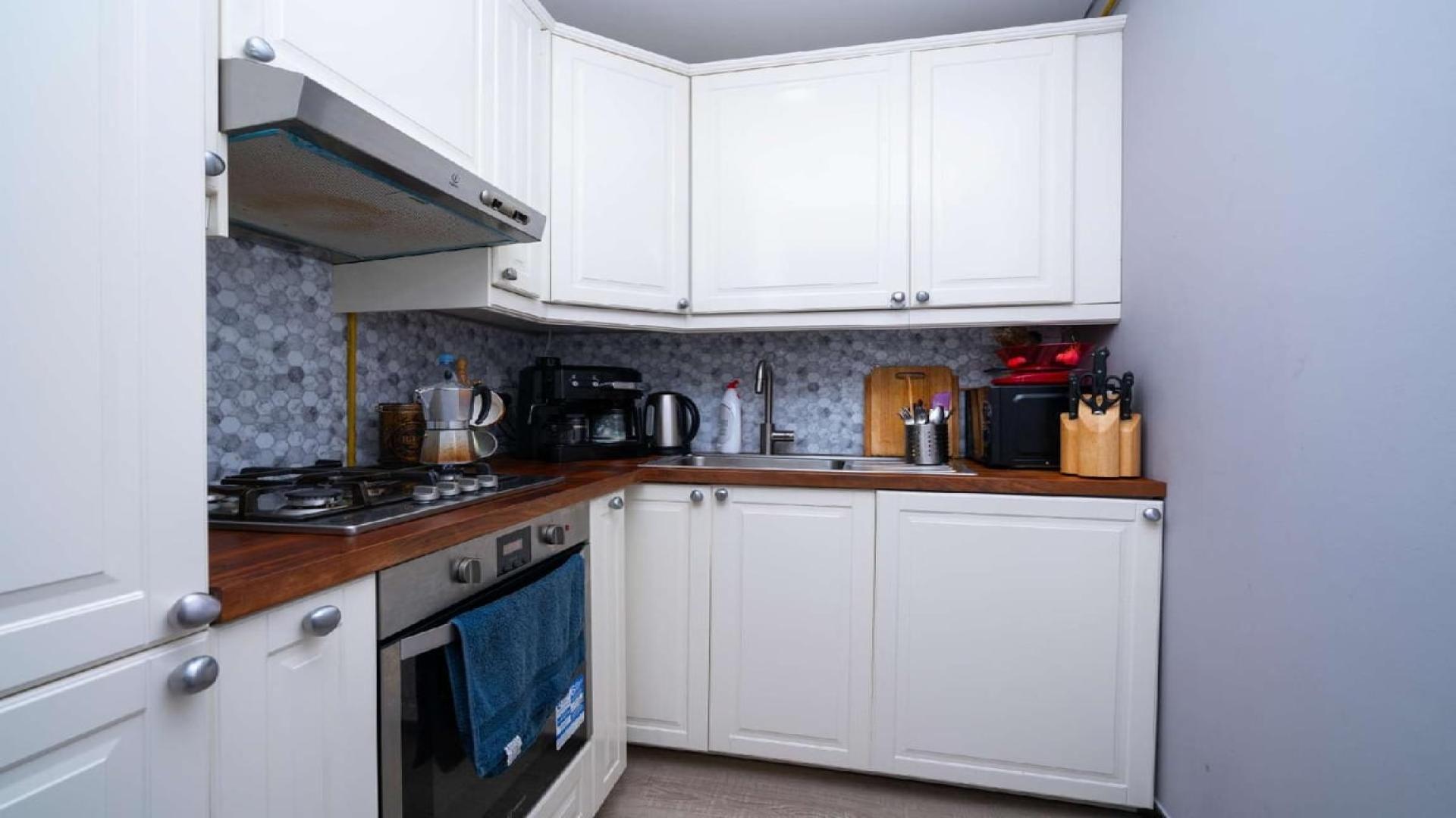 Fully furnished living room with red sofa and TV in JVC apartment, Dubai