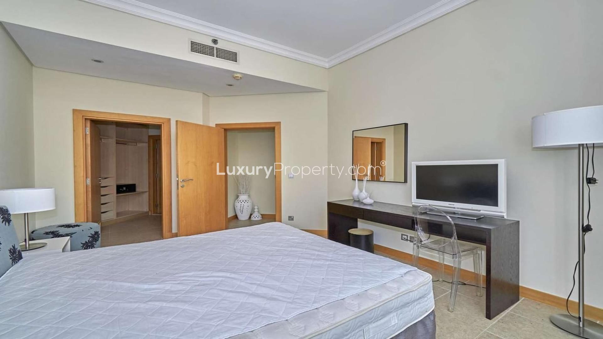Furnished bedroom in Shoreline Apartments, Palm Jumeirah, with TV, desk, and open closet