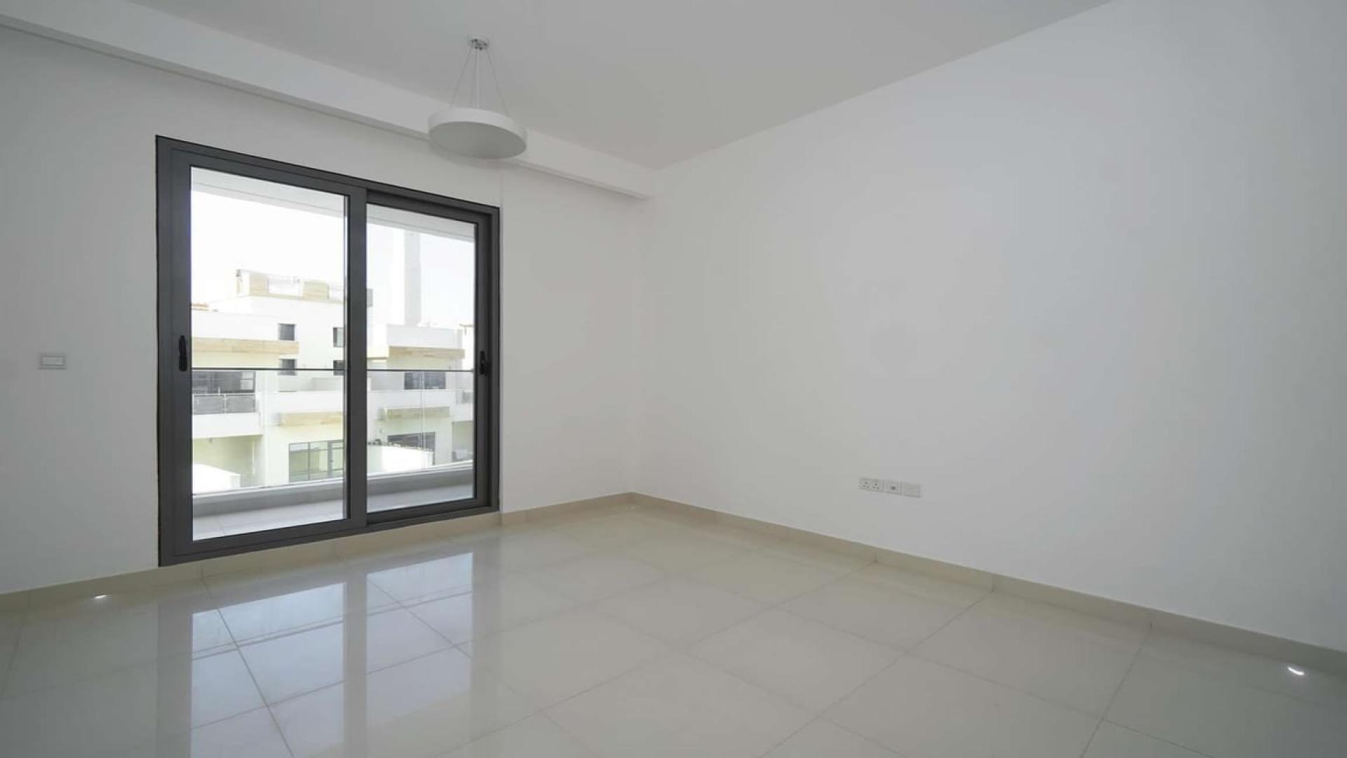 Empty room with large window in Jumeirah Village Circle apartment, Al Manal Elite
