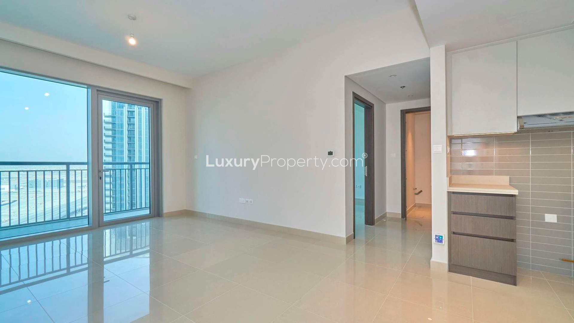 Empty living area in Dubai Creek Harbour apartment with balcony and modern kitchen