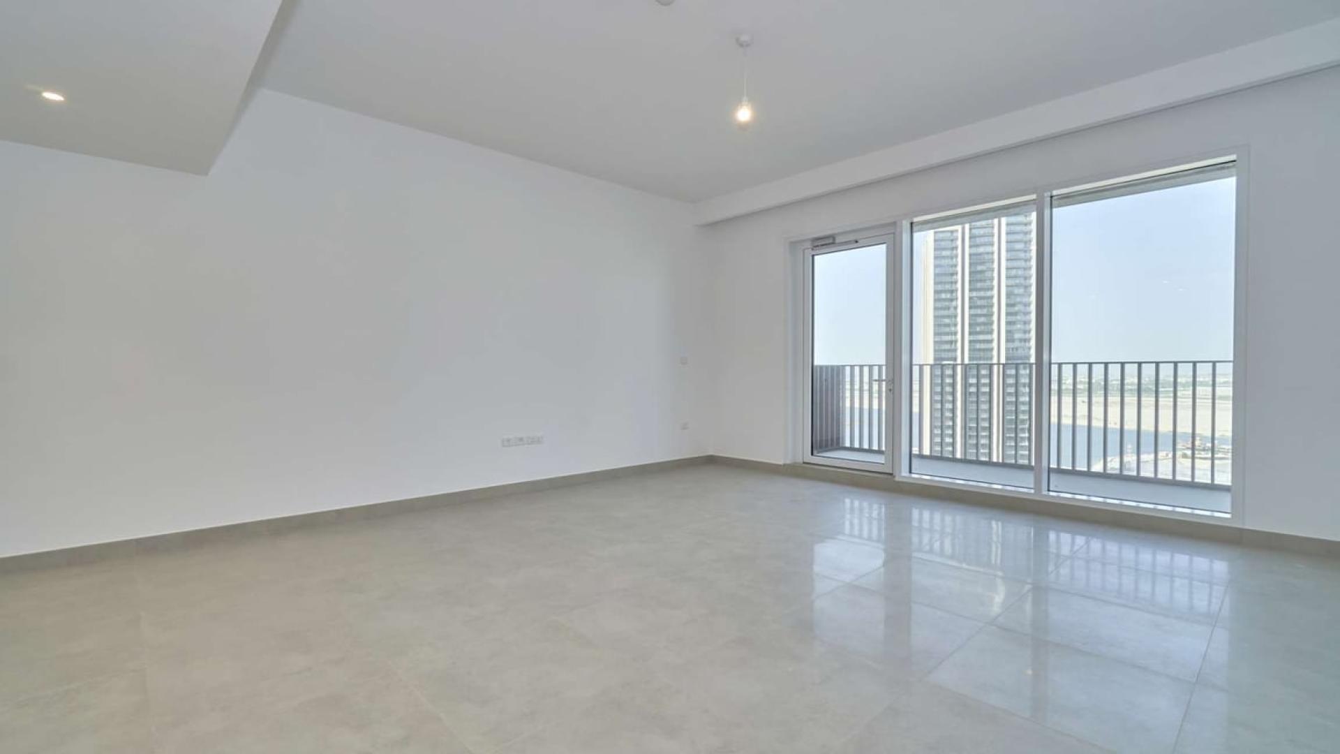 Empty living room with large windows and park views in Dubai Creek Harbour apartment