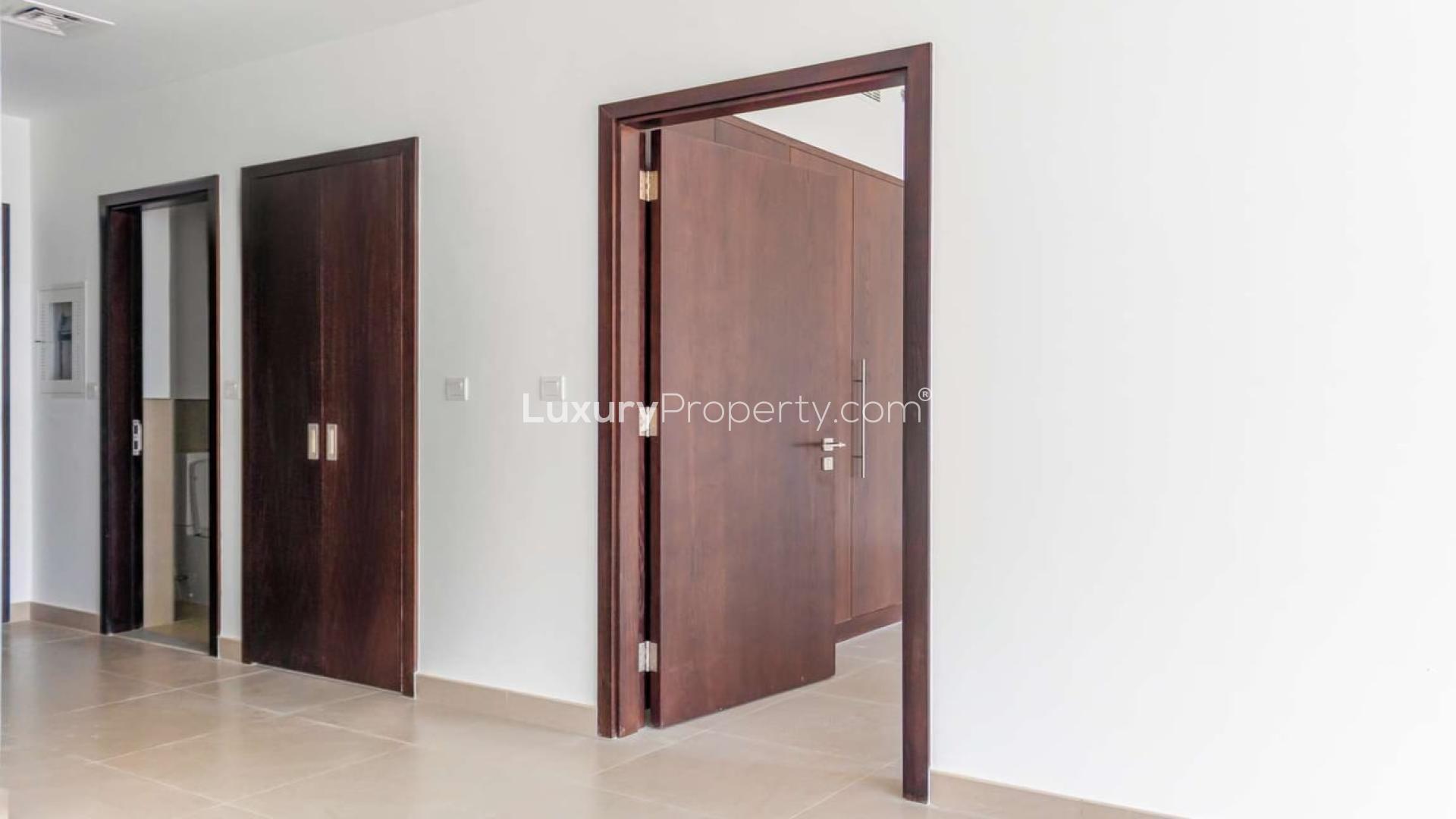 Interior view of modern apartment hallway with wooden doors in Bellevue Towers, Downtown Dubai
