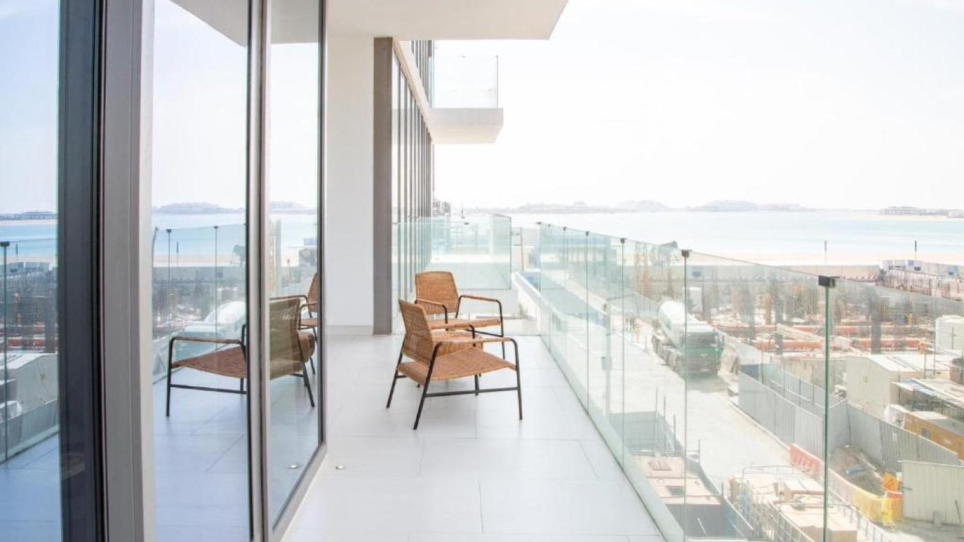 Modern kitchen in Palm Jumeirah apartment, featuring sleek white cabinets and island stove