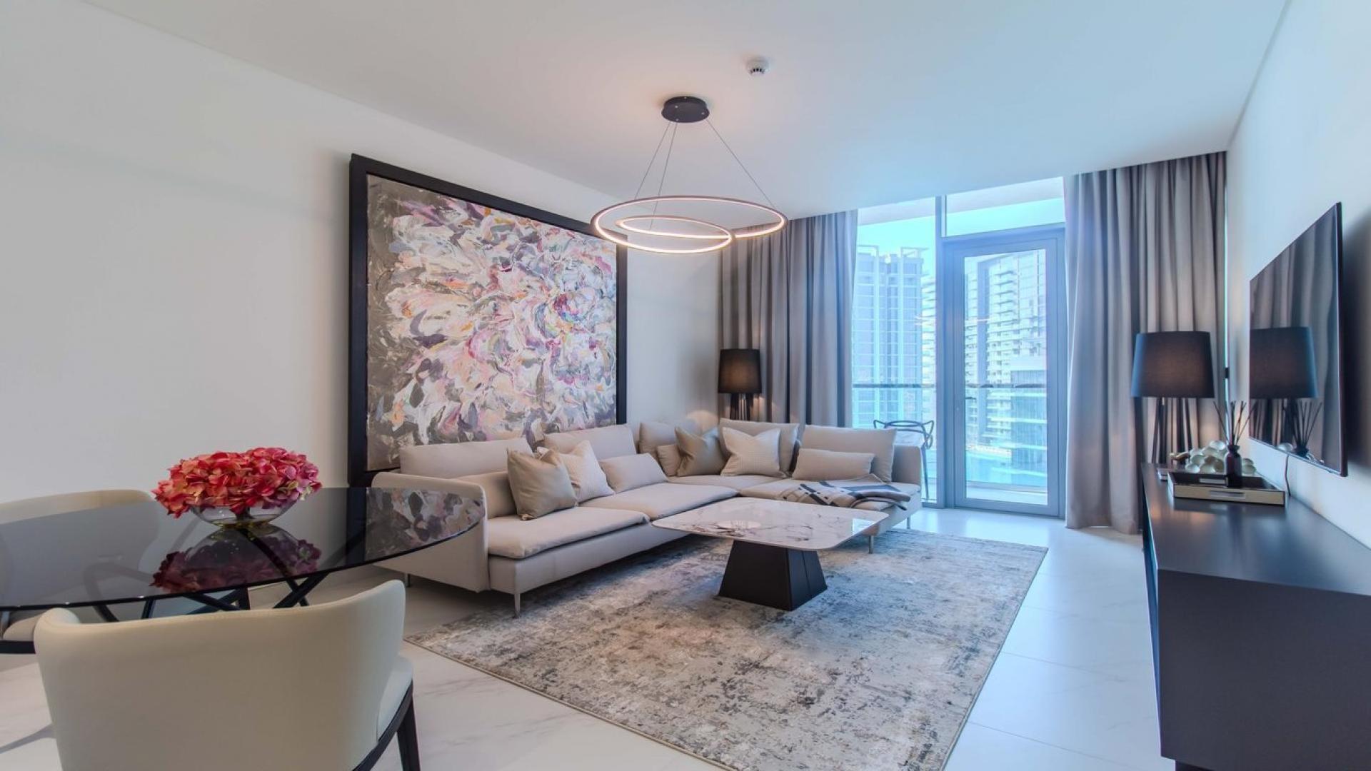 Furnished apartment living room with modern decor, large windows, and lagoon view in District One