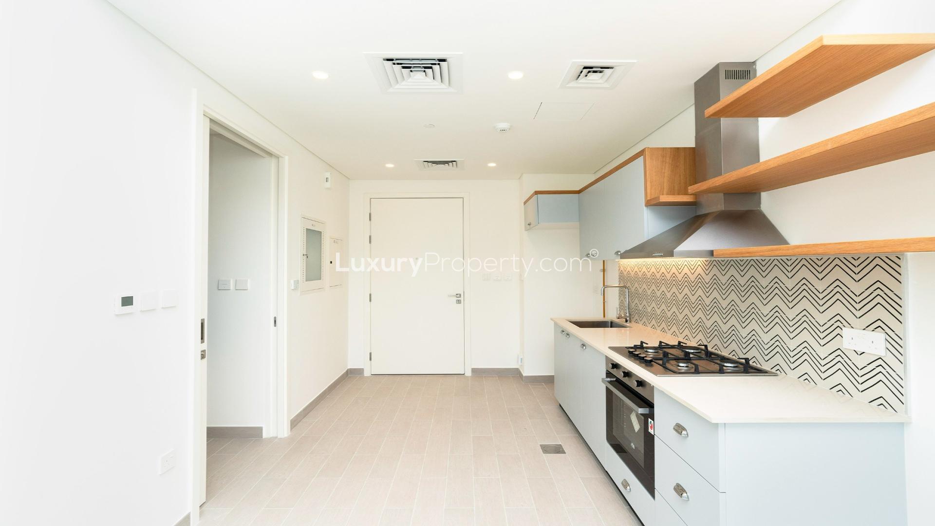 Modern kitchen in Golfville apartment, Dubai Hills Estate, featuring sleek cabinetry and tile backsplash