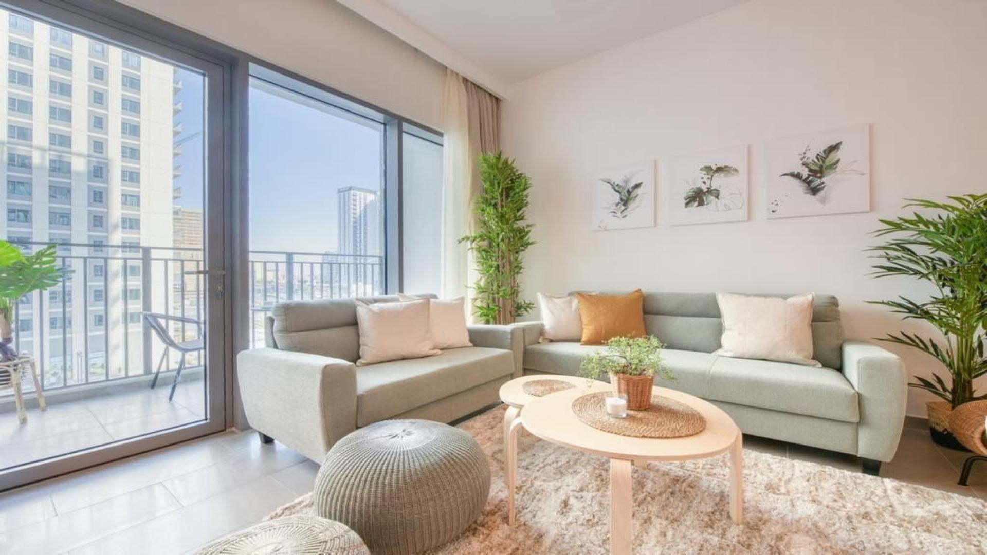 Furnished living room with natural light and balcony view in Dubai Hills Estate apartment