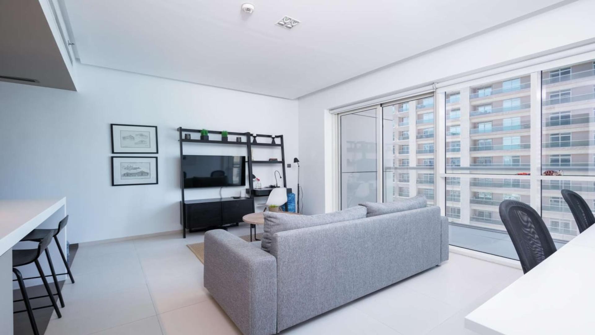 Modern living room in Dubai Marina apartment with city views through large windows