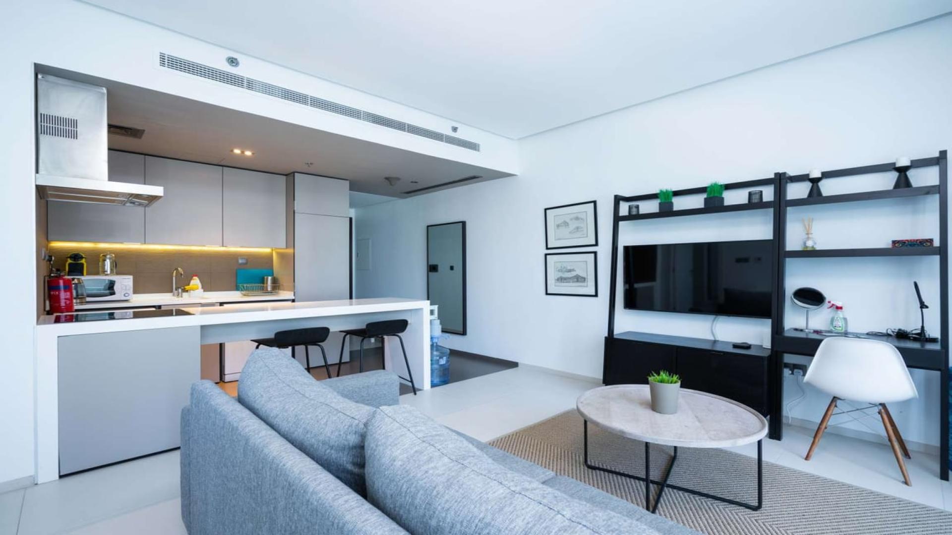 "West Avenue Tower apartment building exterior in Dubai Marina with city views.",Modern open-plan living area in West Avenue Tower apartment, Dubai Marina, with sleek kitchen