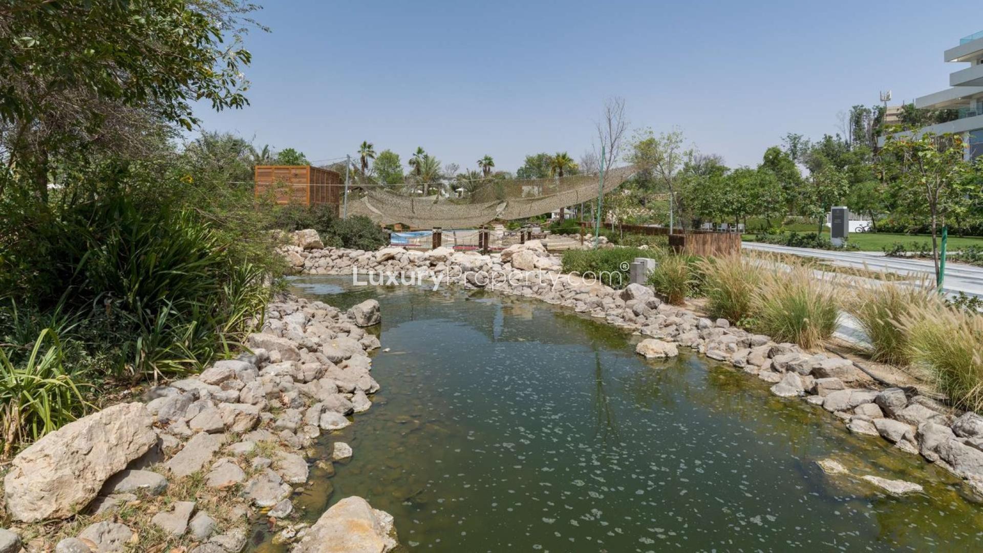 Modern kitchen in Al Barari apartment, featuring wooden cabinetry and sleek countertops