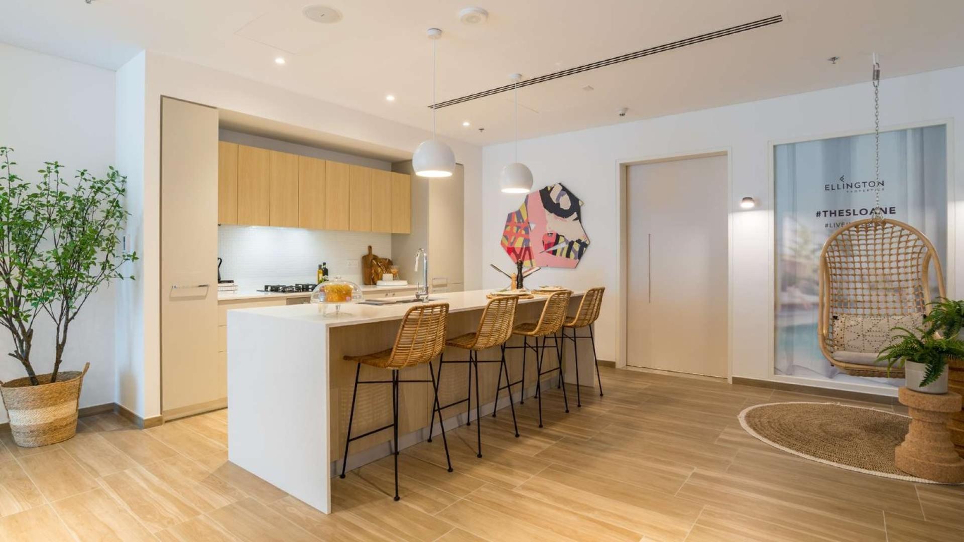 Modern kitchen in JVC apartment, featuring island seating and stylish decor at The Sloane