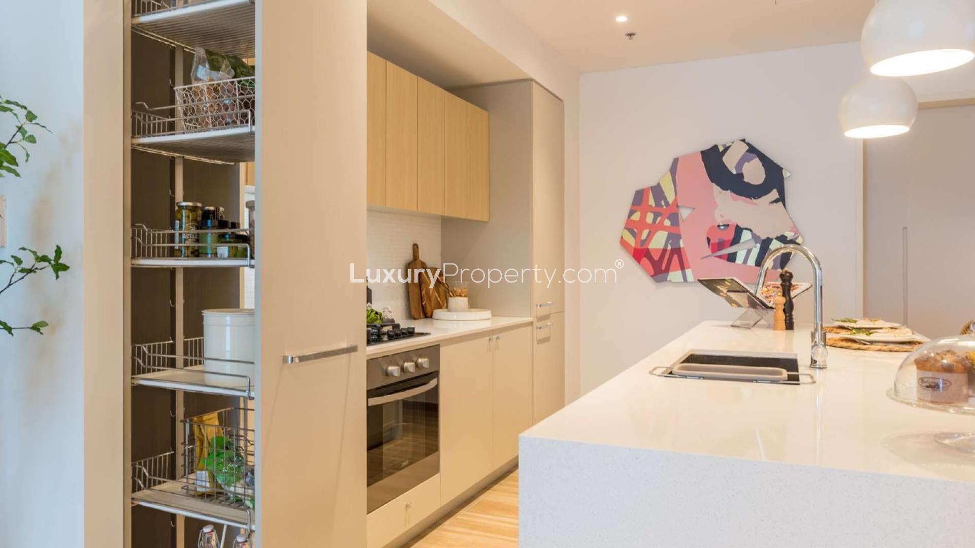 Modern kitchen in two-bed apartment, Jumeirah Village Circle, featuring sleek cabinets and island