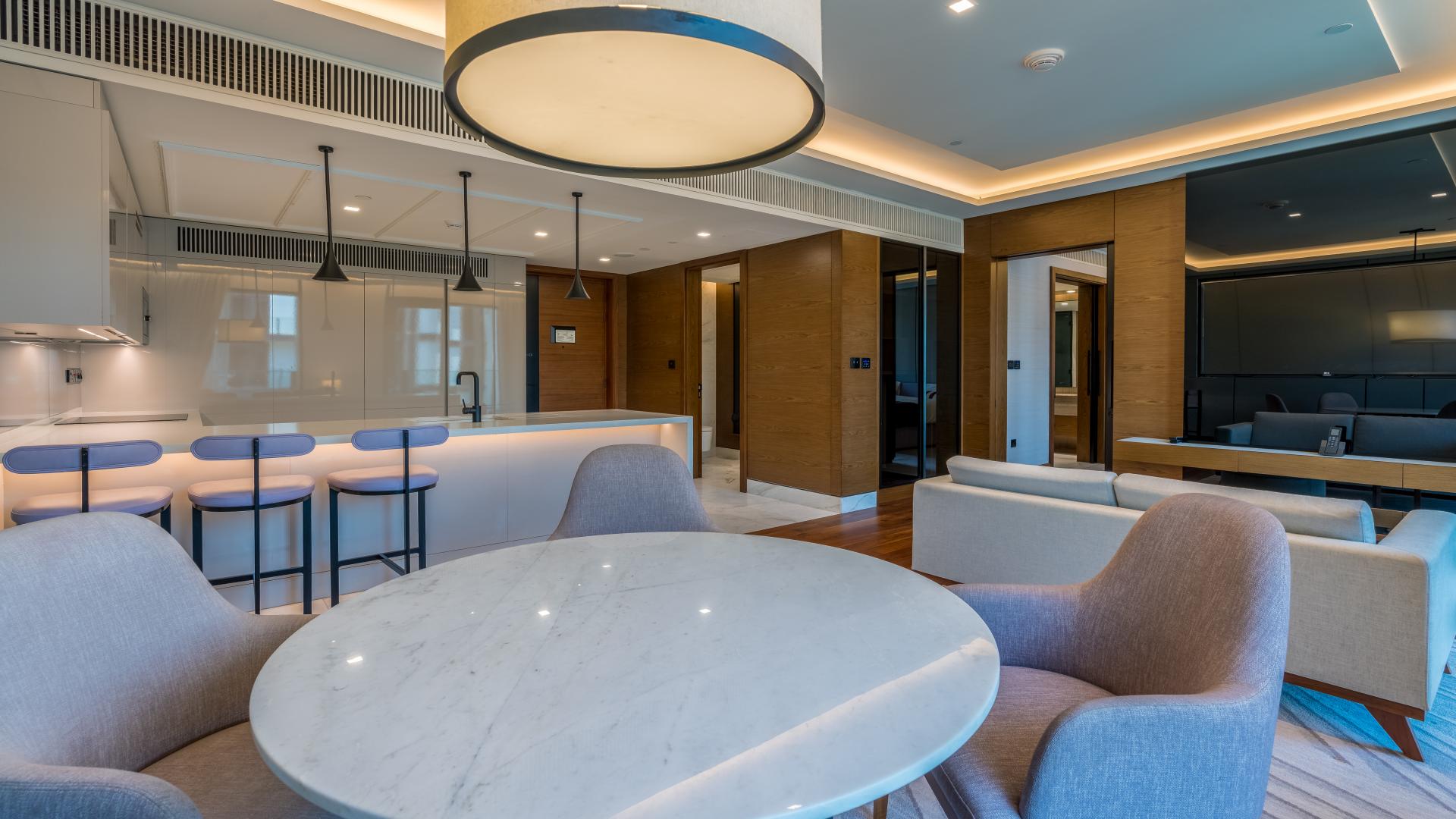 Furnished living area in 1-bedroom apartment, Caesars Bluewaters Dubai, featuring modern kitchen and seating