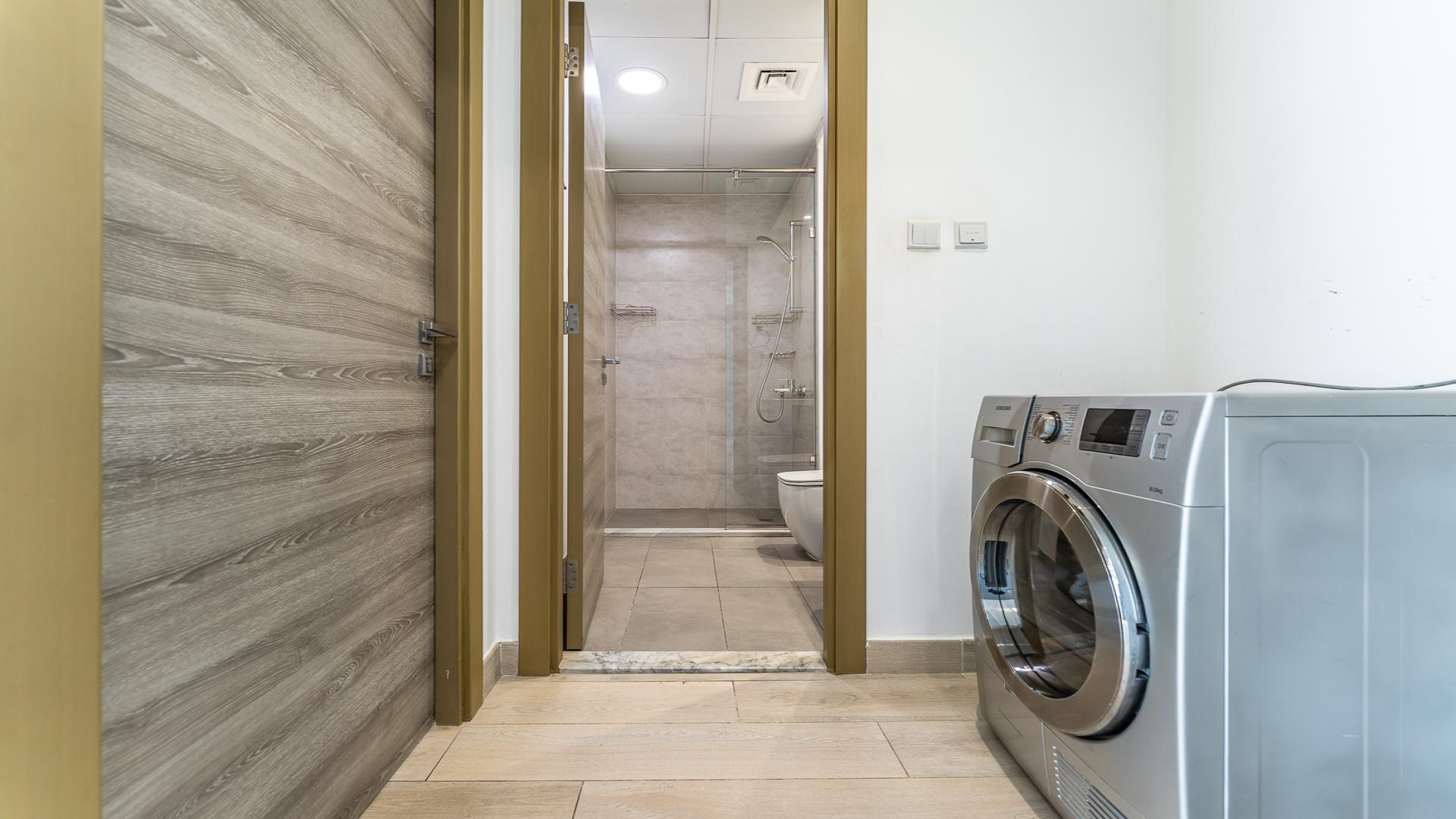 Laundry area with washer and bathroom access in Bloom Towers C apartment, Jumeirah Village Circle