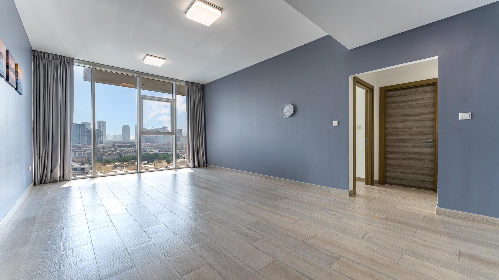"View from Bloom Towers C apartment in Jumeirah Village Circle, overlooking pool and cityscape.",Modern living room with large windows and city view in Bloom Towers C apartment