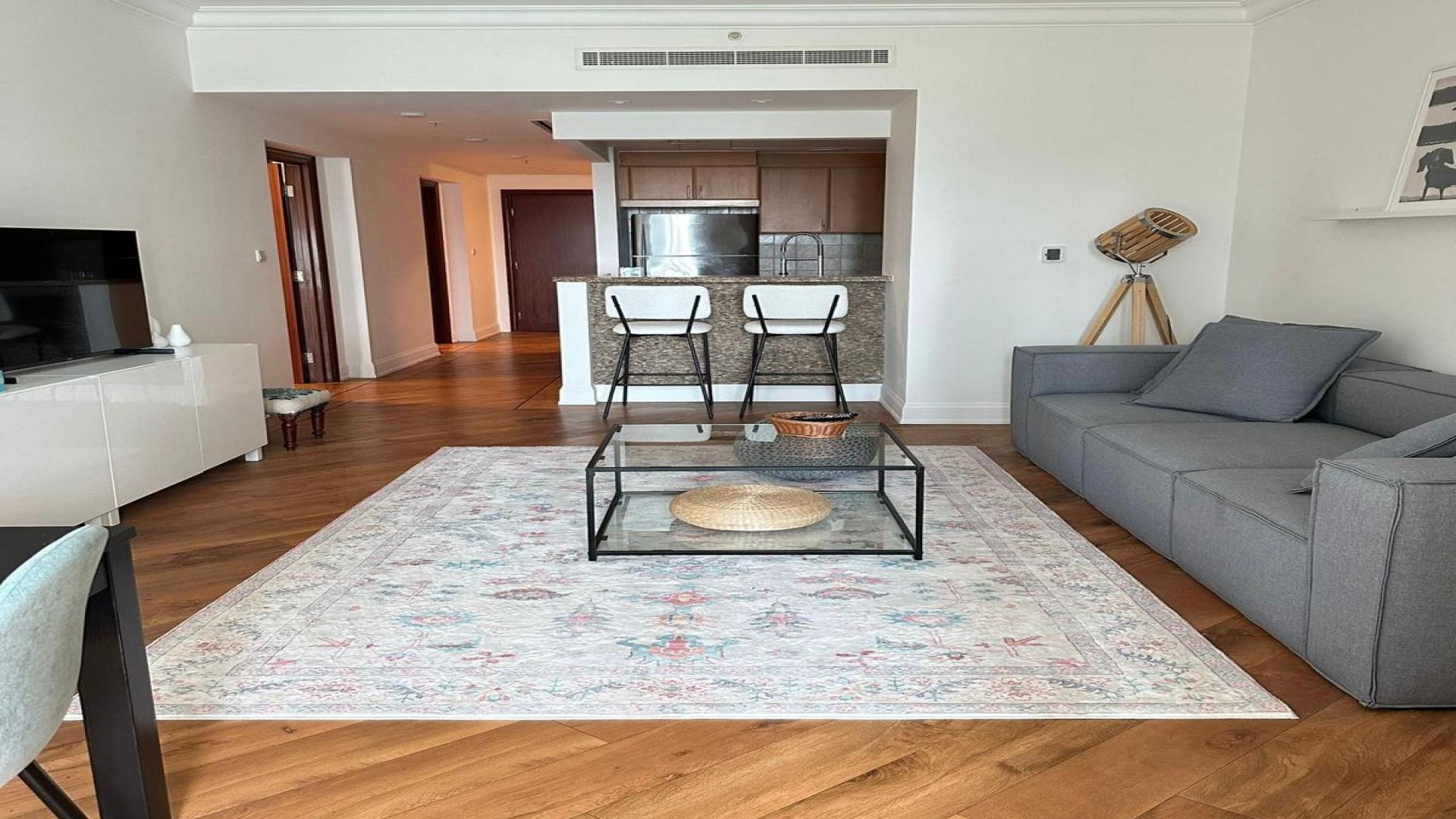 Towering Al Mesk Tower in Dubai Marina with palm trees and blue sky backdrop