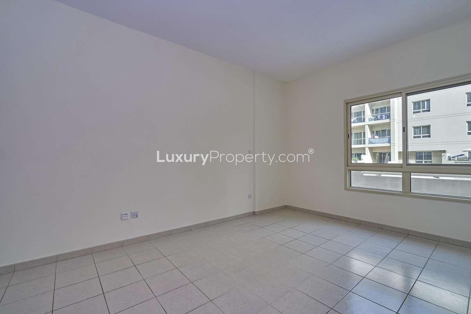 Empty living room in Al Samar apartment with tiled floor and balcony view