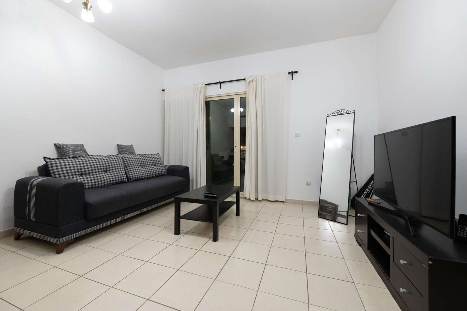 Living room in 1-bedroom apartment, Al Thayyal, The Greens, featuring TV and mirror