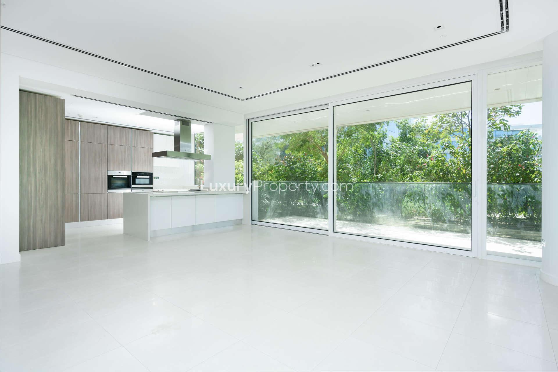 Spacious balcony with glass railing in luxury Ashjar apartment, Al Barari, surrounded by greenery