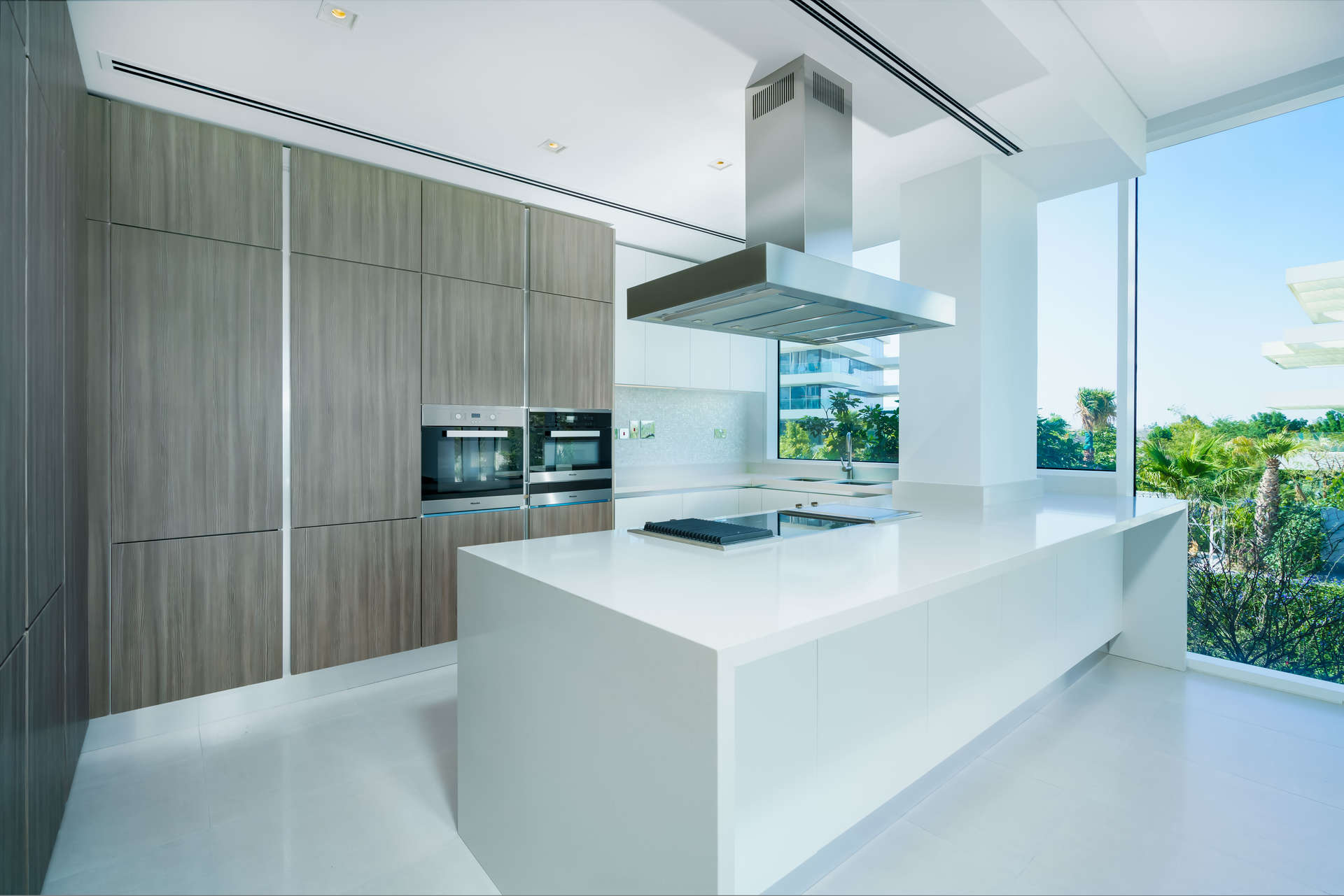 Open-plan living area in 1-bedroom Ashjar apartment, Al Barari, with large windows and modern kitchen