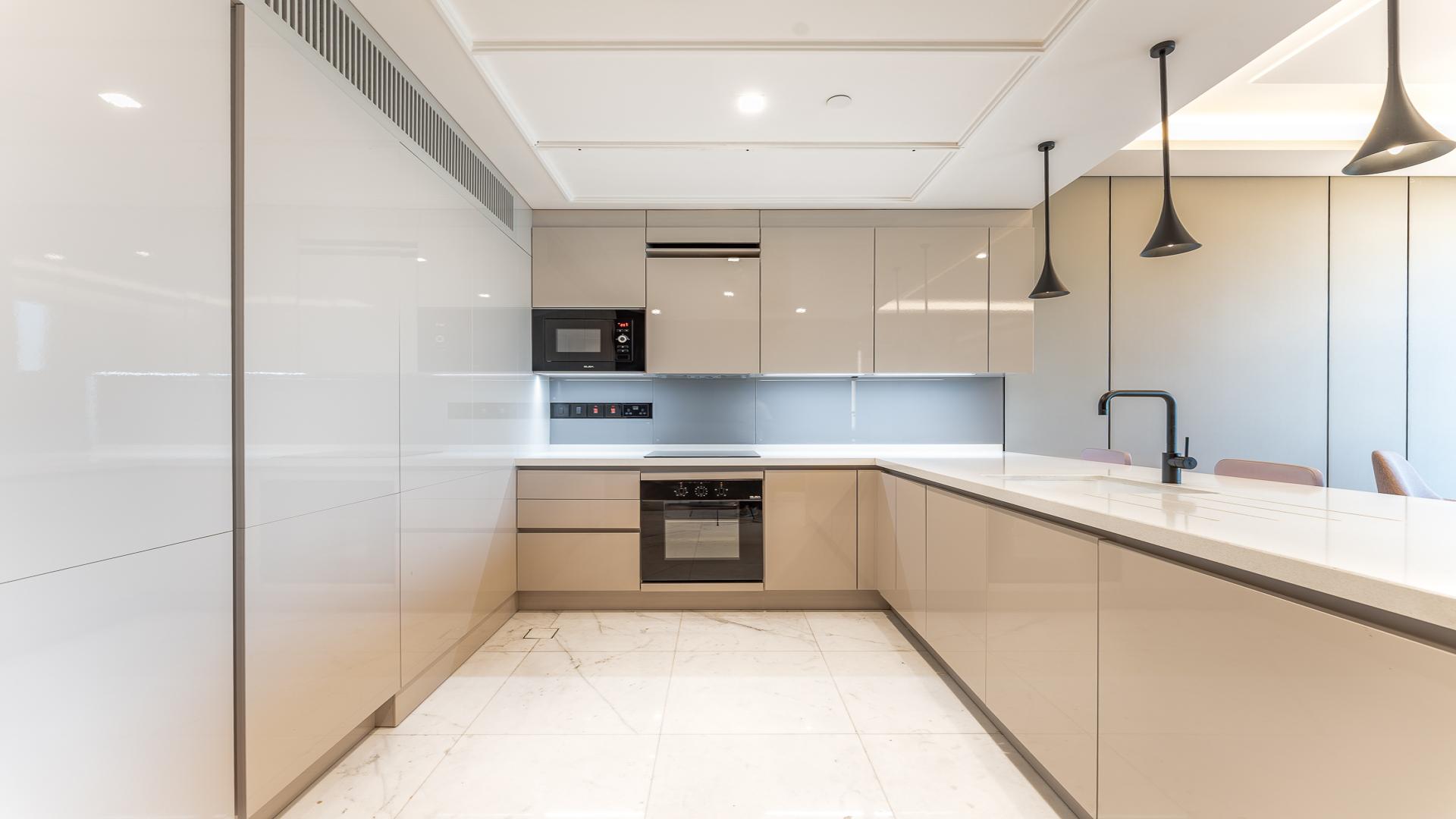 Modern kitchen in Bluewaters apartment for rent, featuring sleek cabinets and island counter