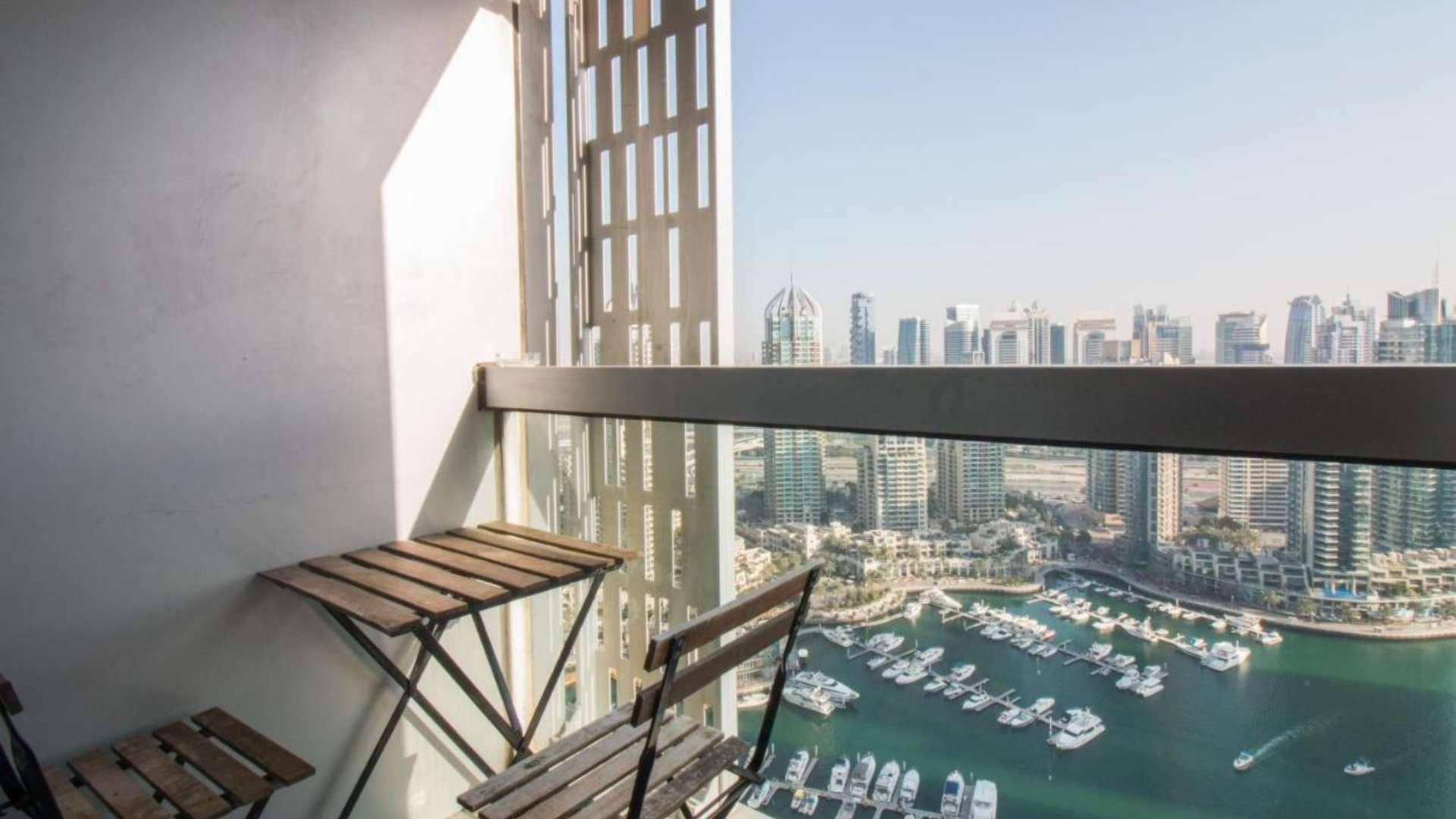Modern furnished living area in Dubai Marina apartment, featuring kitchen and large windows