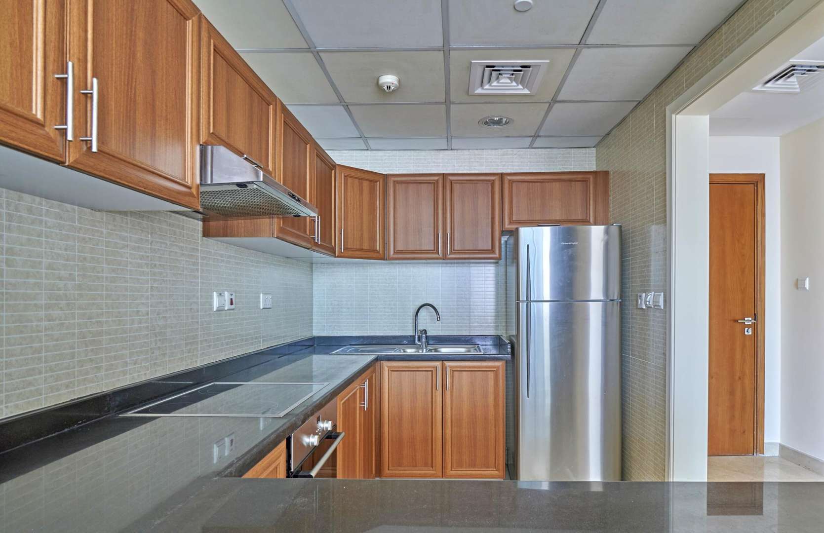 Modern kitchen in one-bedroom apartment, Dorra Bay, Dubai Marina, with wooden cabinets and appliances