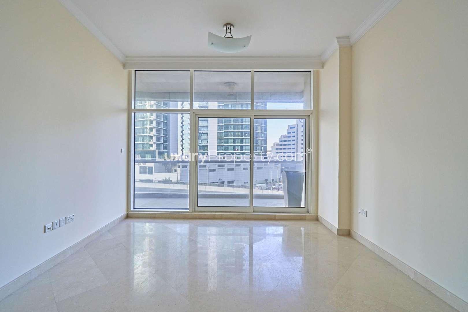 "Modern high-rise apartment building in Dorra Bay, Dubai Marina for rent, exterior view.",Empty living room with large windows in Dorra Bay apartment, Dubai Marina